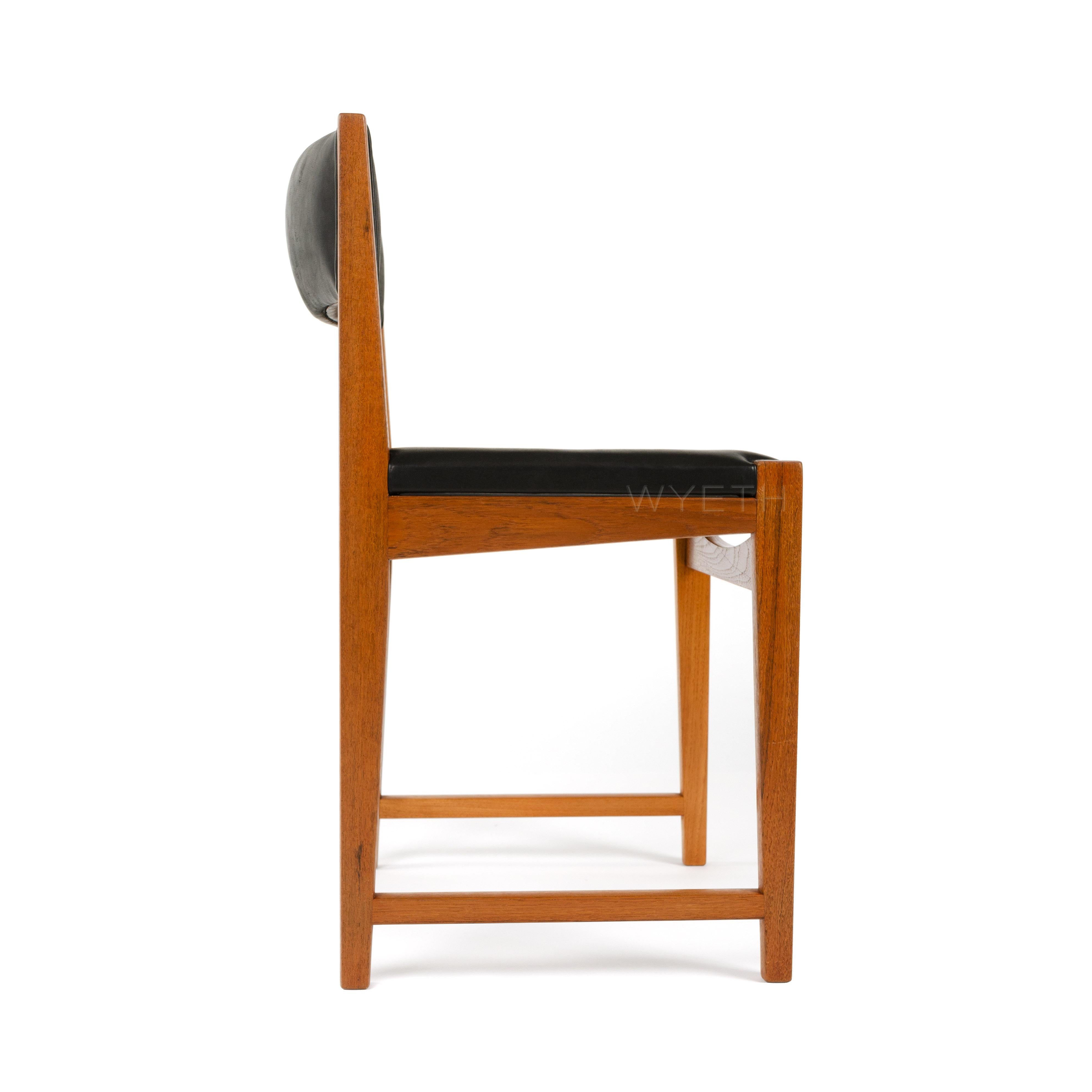 Un ensemble de six chaises de salle à manger en teck avec un nouveau revêtement en cuir noir. L'ensemble comprend deux fauteuils avec détails en bois de rose et huit chaises d'appoint.