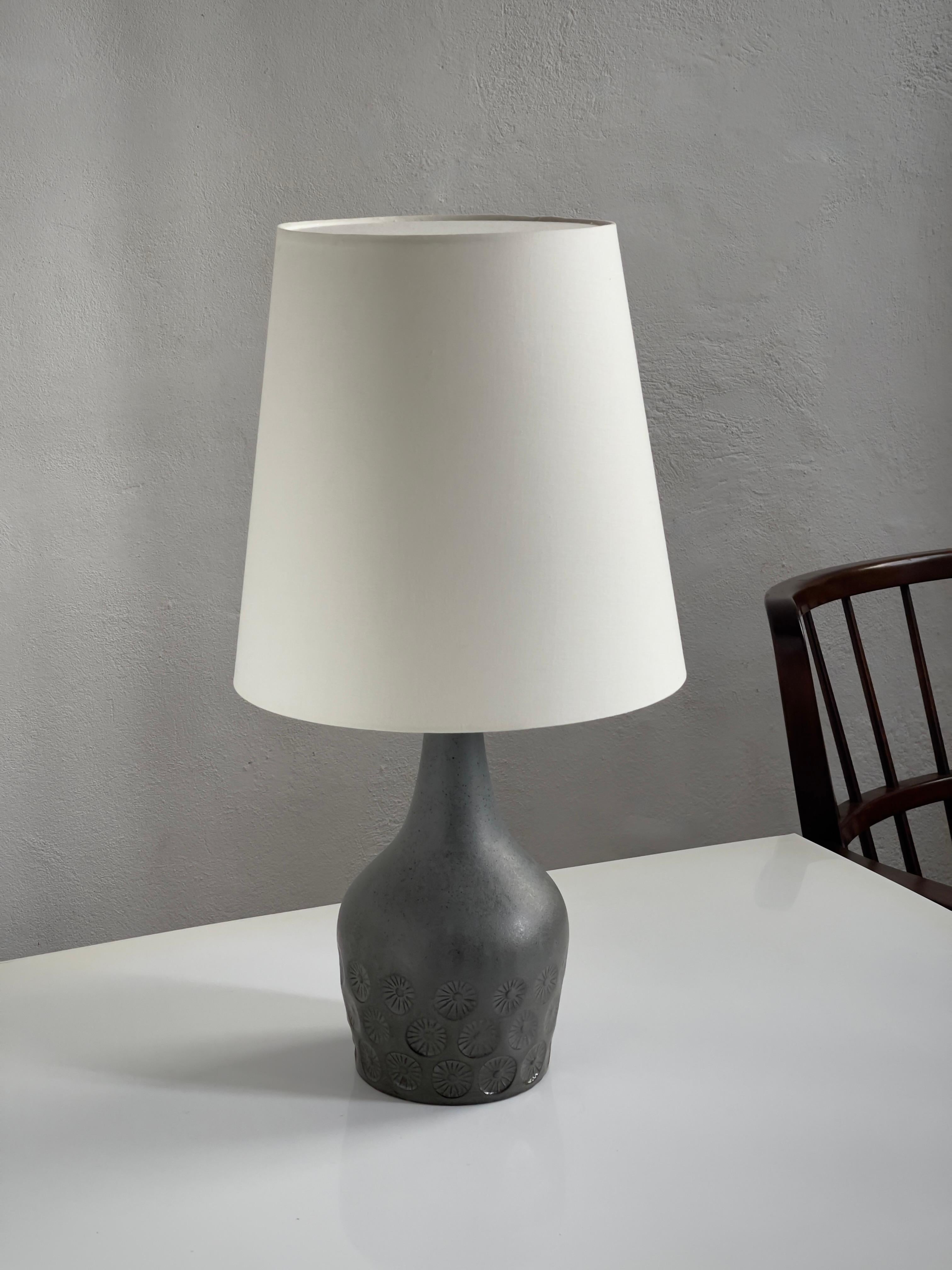 Cette lampe de table danoise en grès des années 1950 est un exemple exquis du design scandinave du milieu du siècle, caractérisé par ses proportions élégantes, ses lignes épurées et ses détails artistiques. La lampe est émaillée dans des tons riches
