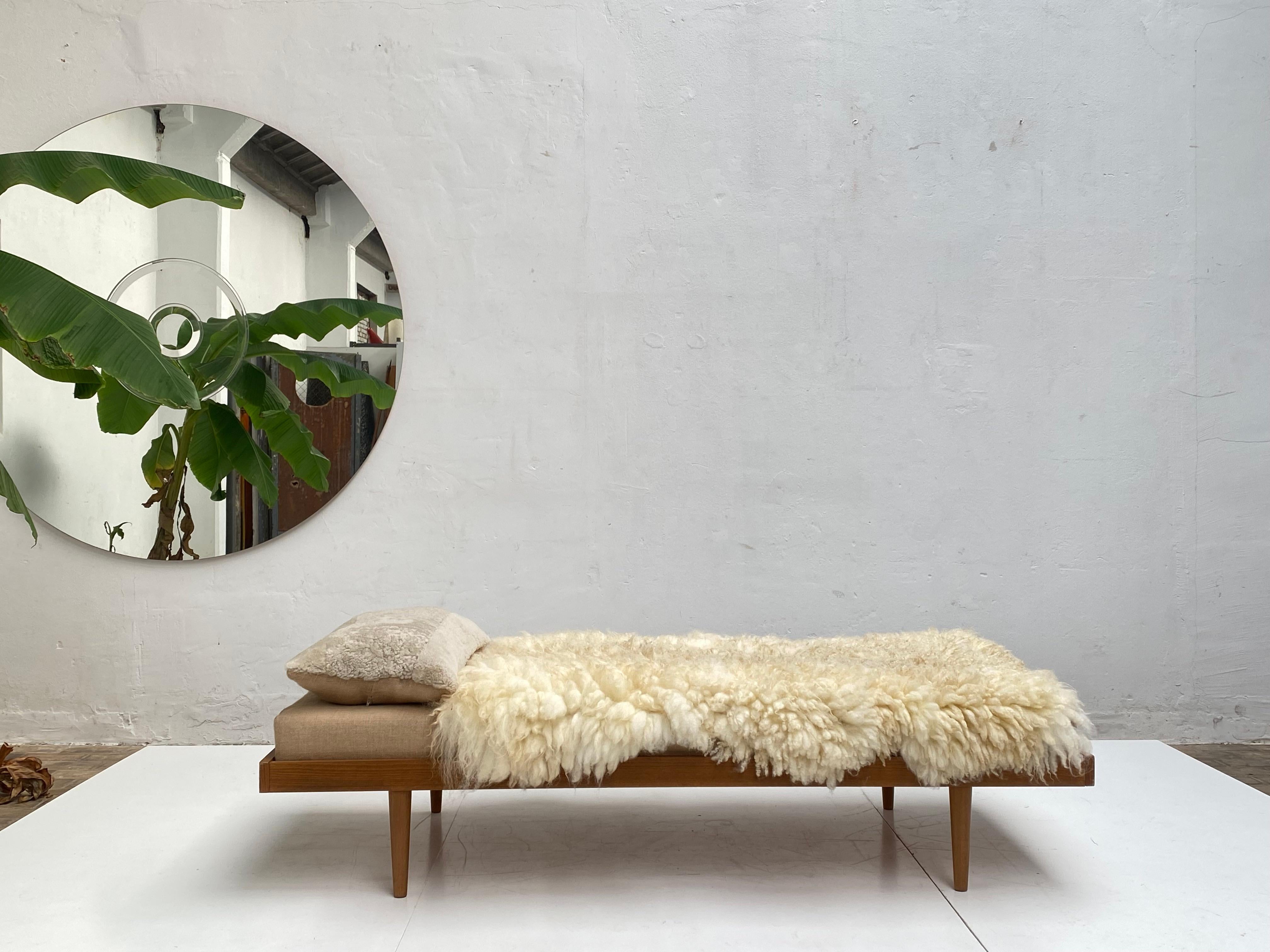 This 1950's Danish minimal Teak wood daybed has been custom upholstered with a raw Cotton mattress & felted wool rug

The wool comes from a cross breed Wensleydale & Texel sheep that has been felted by hand 

Felting wool is a no kill method to