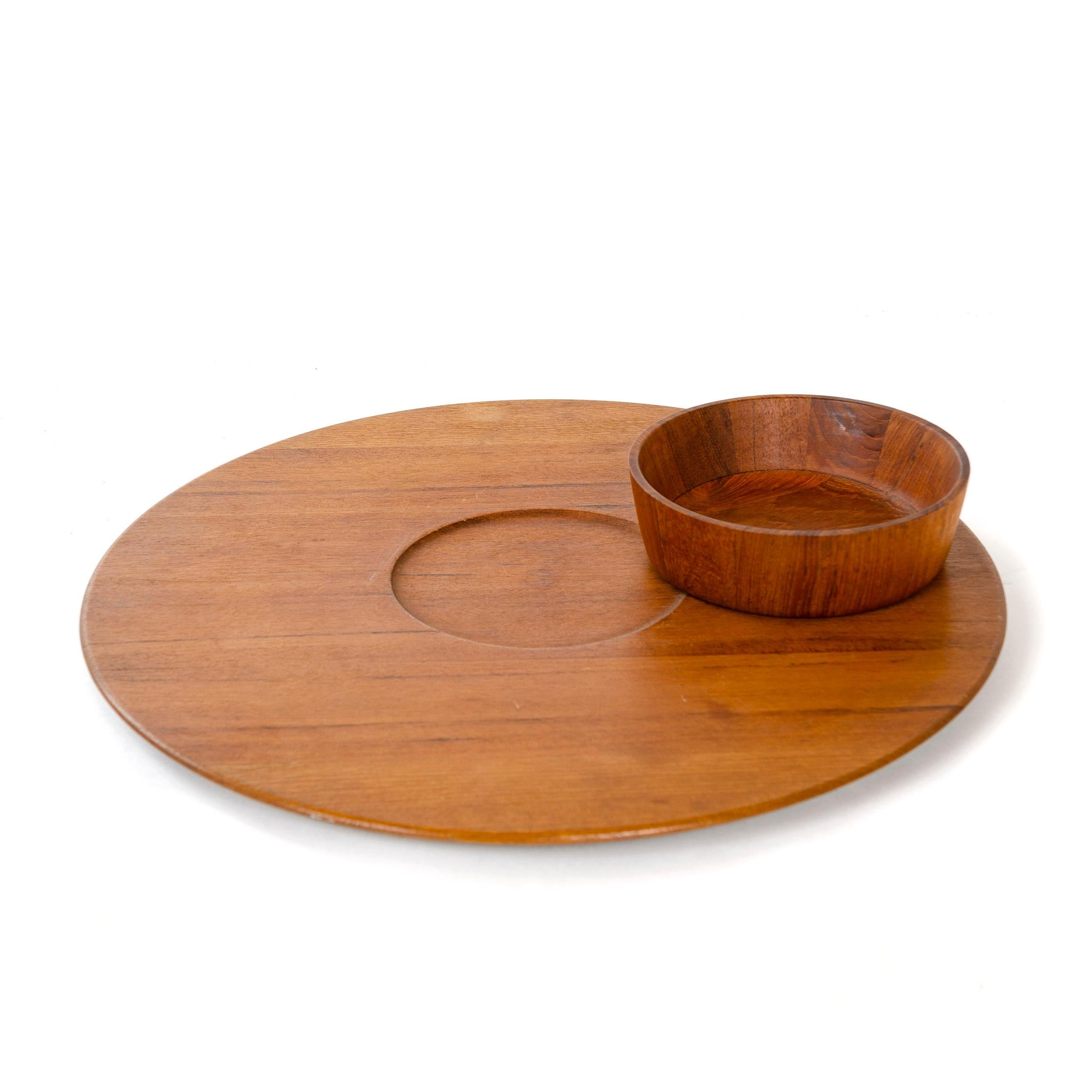 A teak platter with recessed middle and rail feet and accompanying staved teak bowl.