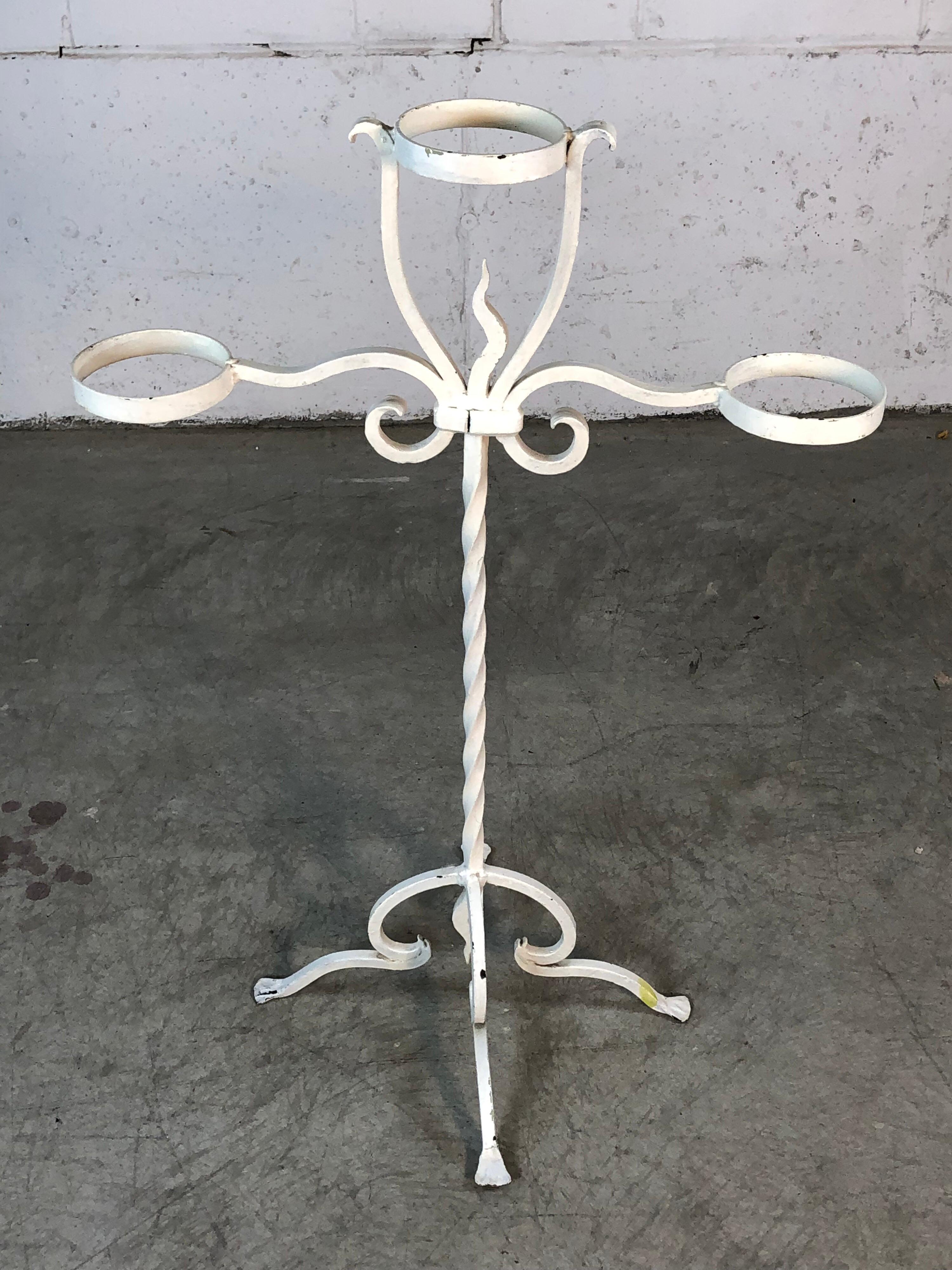 1950s solid wrought iron plant stand that holds three flower pots. The stand has been painted white and is very heavy. Has really nice decorative accents. No maker’s mark. Holds a 5”diameter pot, pot shown is not included.