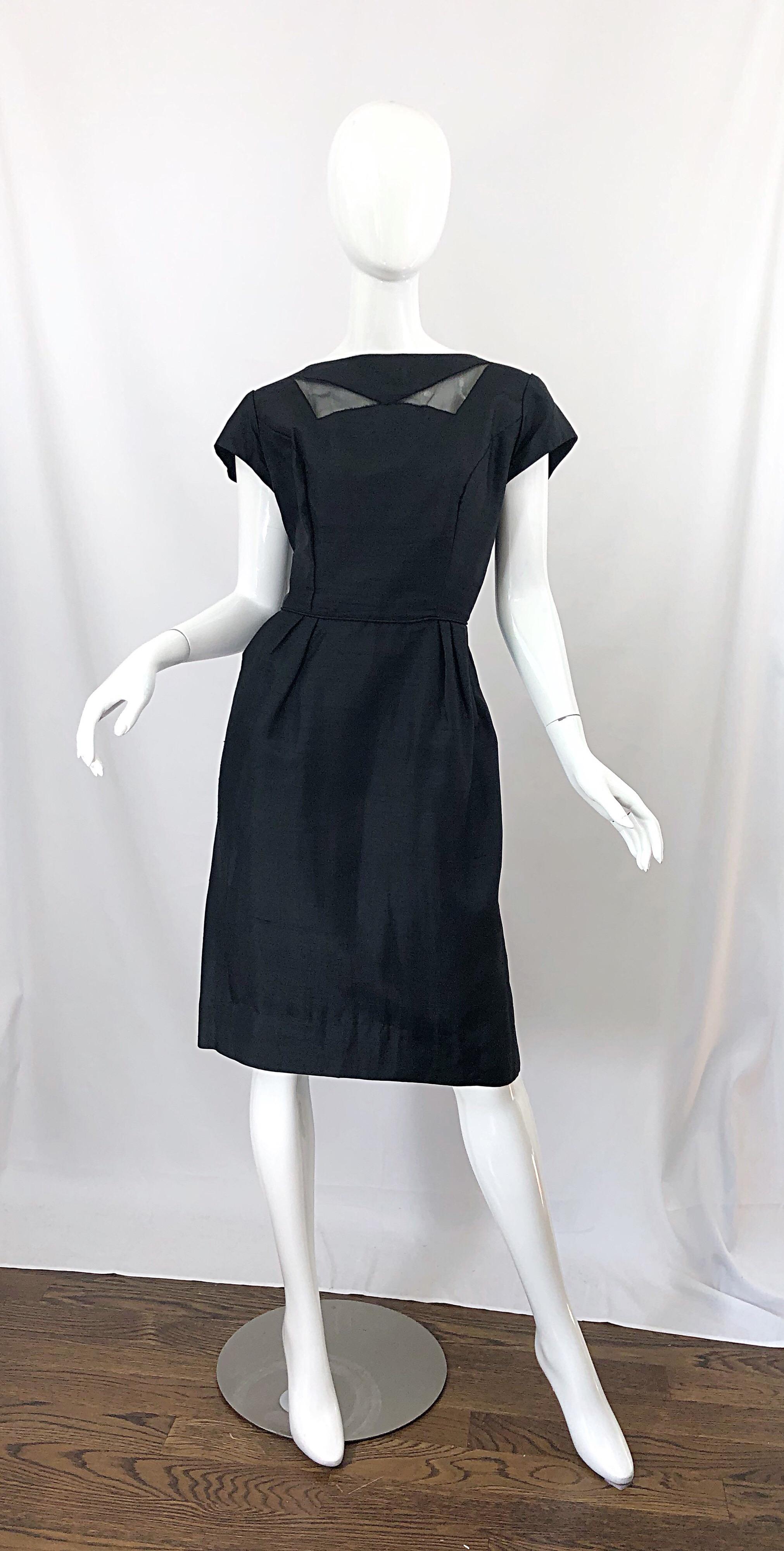 Chic 1950s demi couture black silk cut-out cocktail dress! Features a fitted bodice and forgiving skirt. Low cut back features a large bow that snaps on one side. Full metal zipper up the back with hook-and-eye closure. Cut outs at the top neck