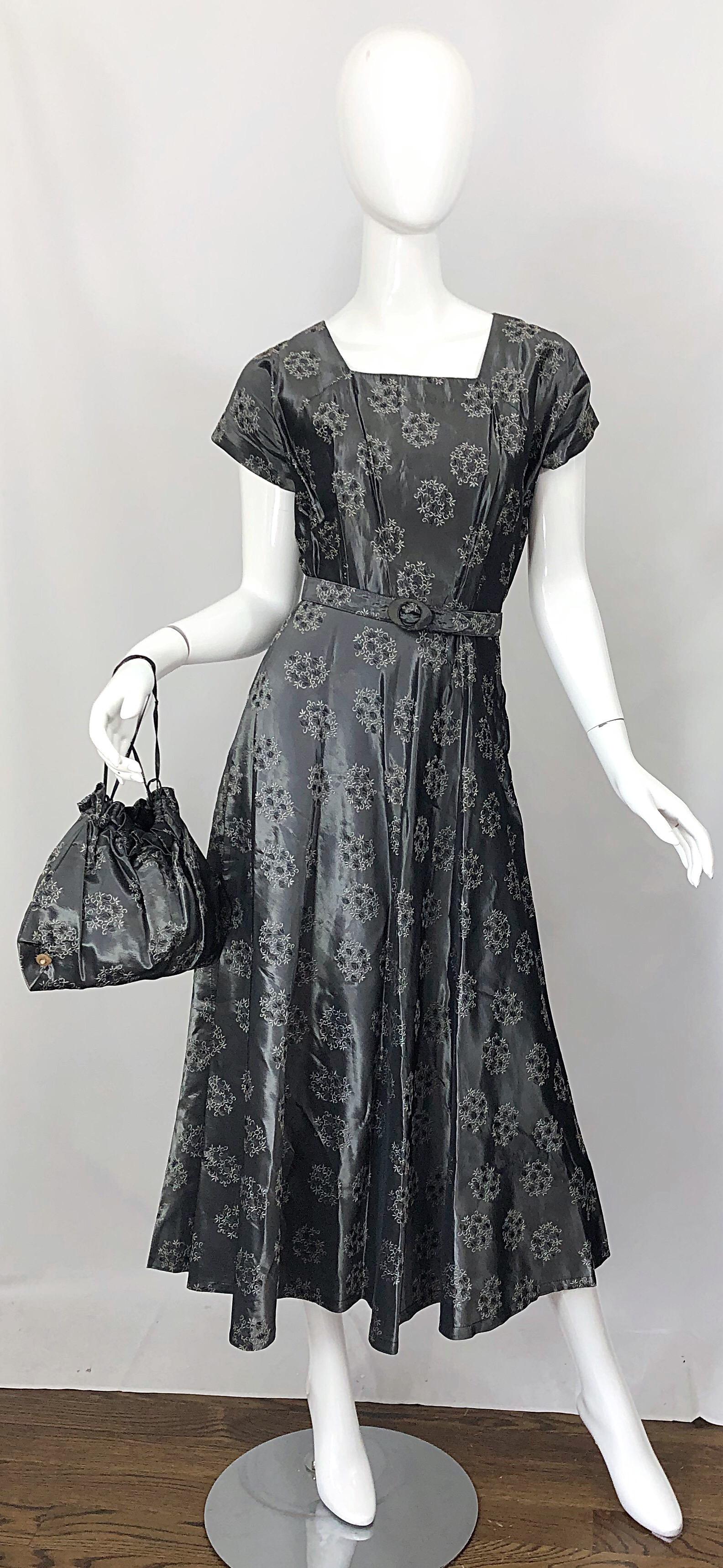 Magnifique ensemble robe et sac à main en taffetas de soie gris argenté / gunmetal des années 50 ! Il se caractérise par une belle couleur gunmetal avec juste ce qu'il faut de légère brillance. Des fleurs sont imprimées tout au long de l'ouvrage.