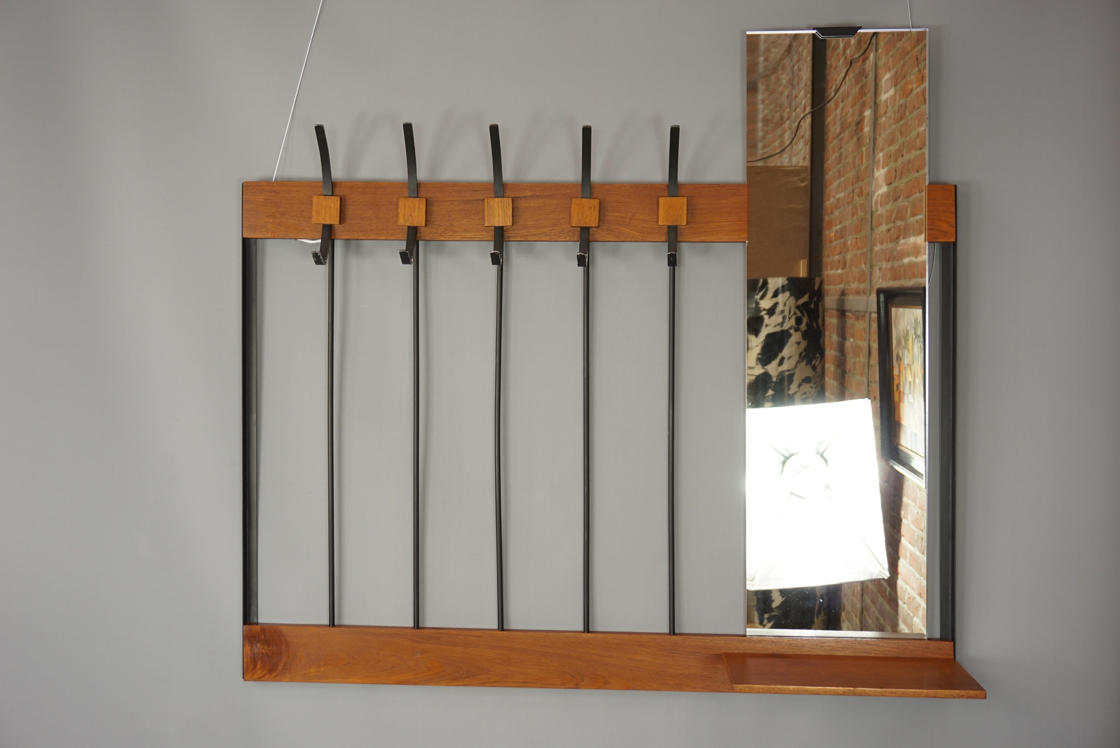 Practical, industrial look and Scandinavian style for this 1950s design wall-mounted coat rack composed of a black metal structure, with assorted coat hooks, a wooden little storage and a rectangular mirror. It will be the new companion of your