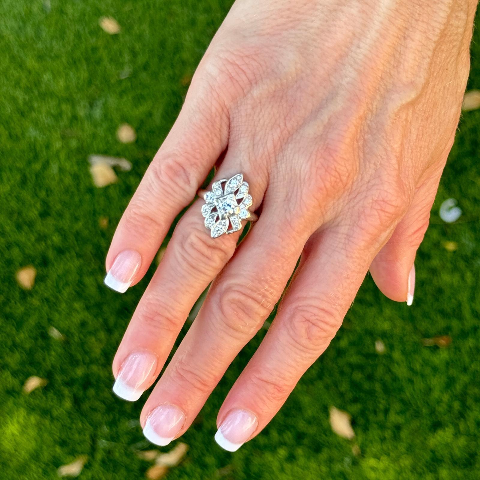 This stunning 1950's vintage cocktail ring handcrafted in 14 karat white gold is an example of timeless elegance and glamour. The ring is adorned with an approximate .38 carat Old European cut center diamond and 16 accent diamonds weighing another