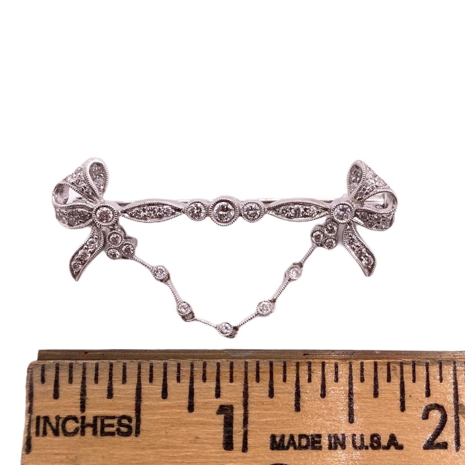 1950's diamond bow pin fashioned in 18 karat white gold. The pin features round brilliant cut diamonds weighing .50 carat total weight and graded F-G color and VS clarity. The brooch measures 1.75 inches in length. 