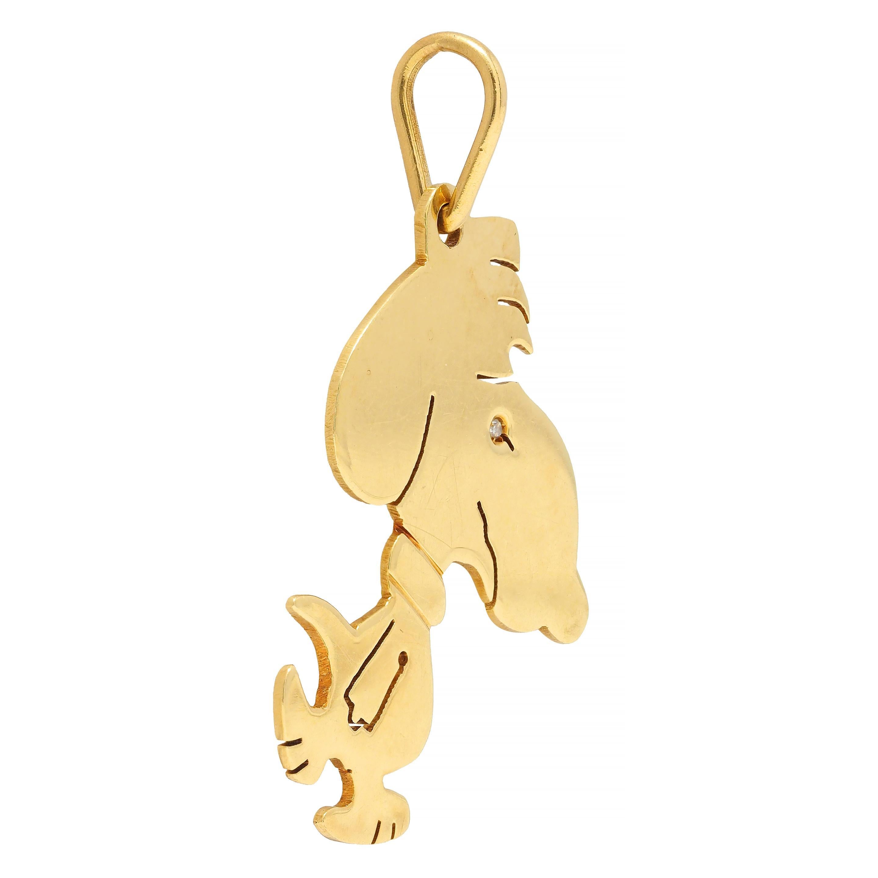 Designed as the cartoon character Snoopy in gold with pierced details 
Shown in profile with crooked smile, fluffed hair, and wearing a collar
Accented by a flush set single cut diamond eye 
Weighing approximately 0.01 carat - eye clean and