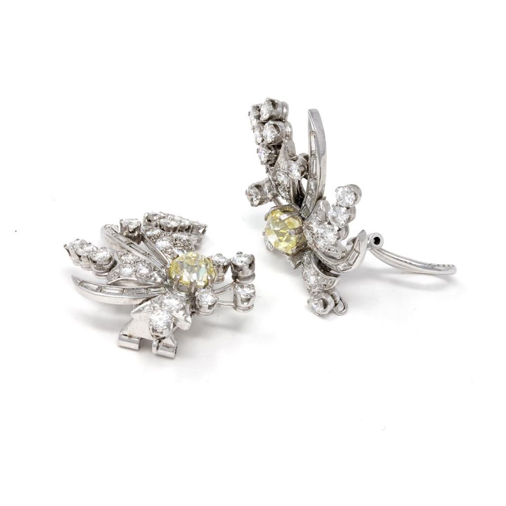 Paar Ohrringe aus Platin und Diamanten mit Clipverschluss, um 1950, in Form von Blumenranken, die in der Mitte mit 2 runden hellgelben Diamanten im Altminenschliff mit einem Gewicht von je ca. 1,10 Karat besetzt sind. Weiter mit runden und