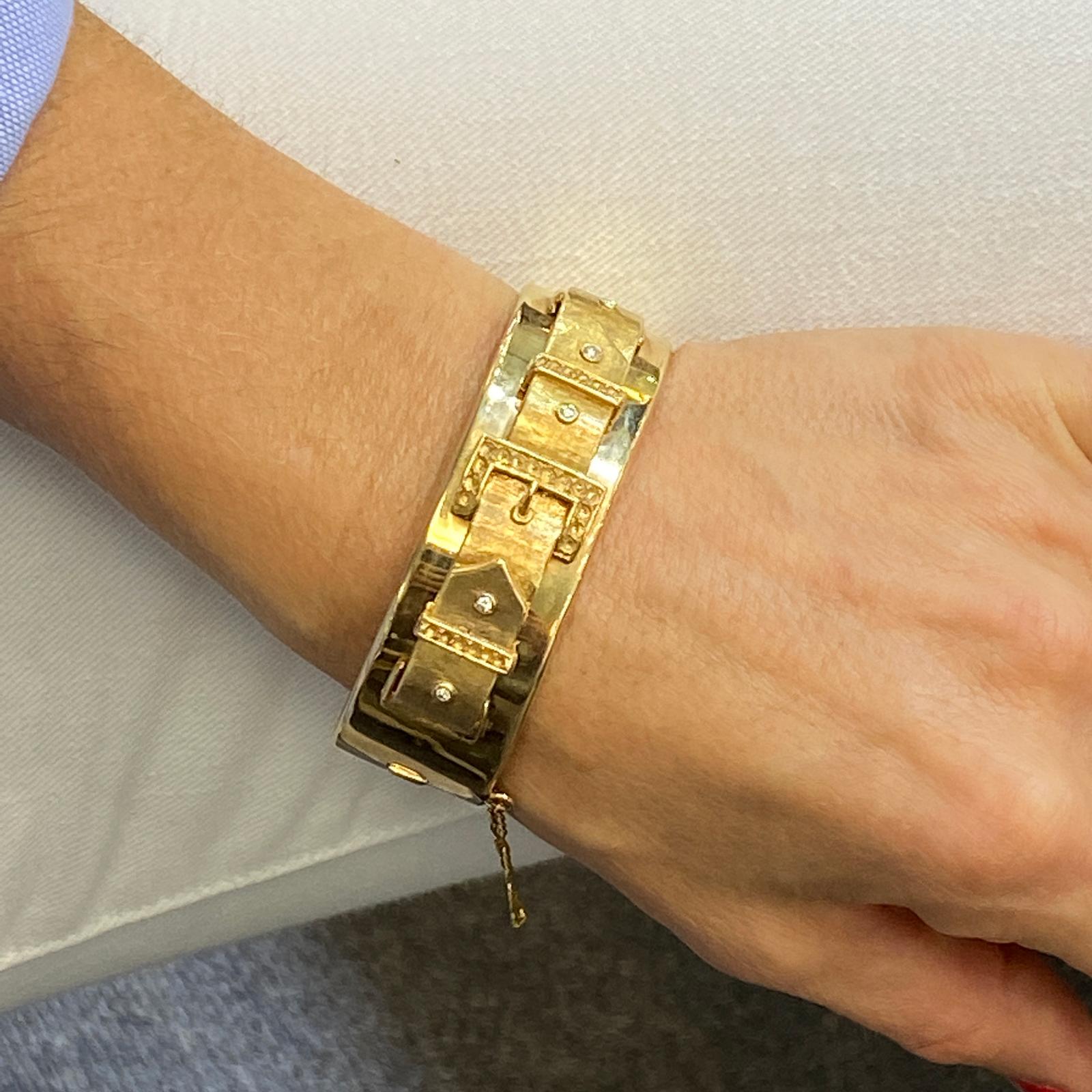 Fabulous 1950's hinged bangle bracelet fashioned in 14 karat yellow gold. The bangle features a 3D buckle design with 5 diamond accents. The bangle measures 7 inches in internal circumference, and .75 inches in width. We have left the original