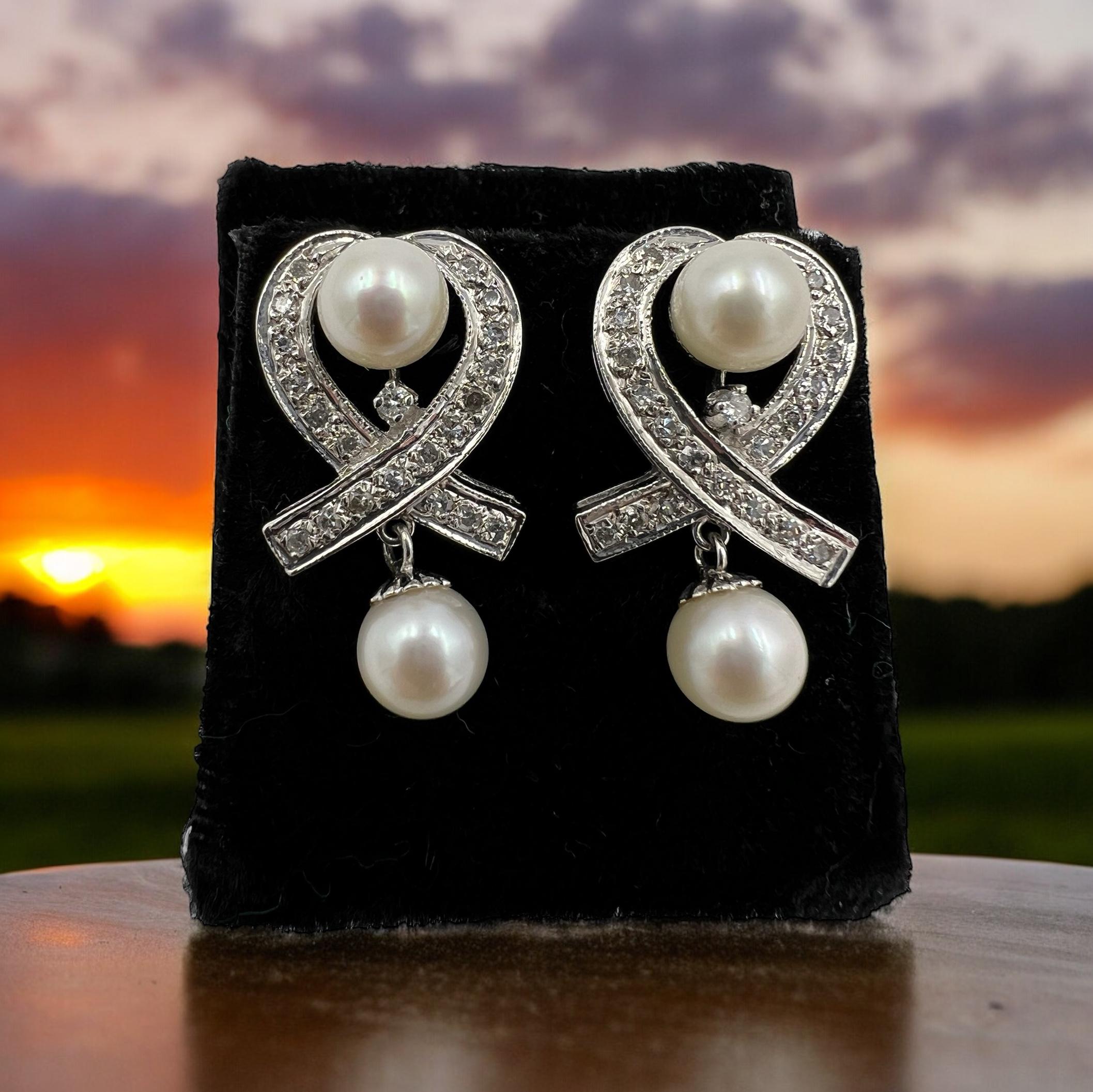 Boucles d'oreilles pendantes en or blanc, diamants et perles, datant des années 1950.

 À l'époque glamour des années 1950, les femmes se paraient de bijoux exquis qui respiraient l'élégance et la sophistication. L'une de ces pièces intemporelles