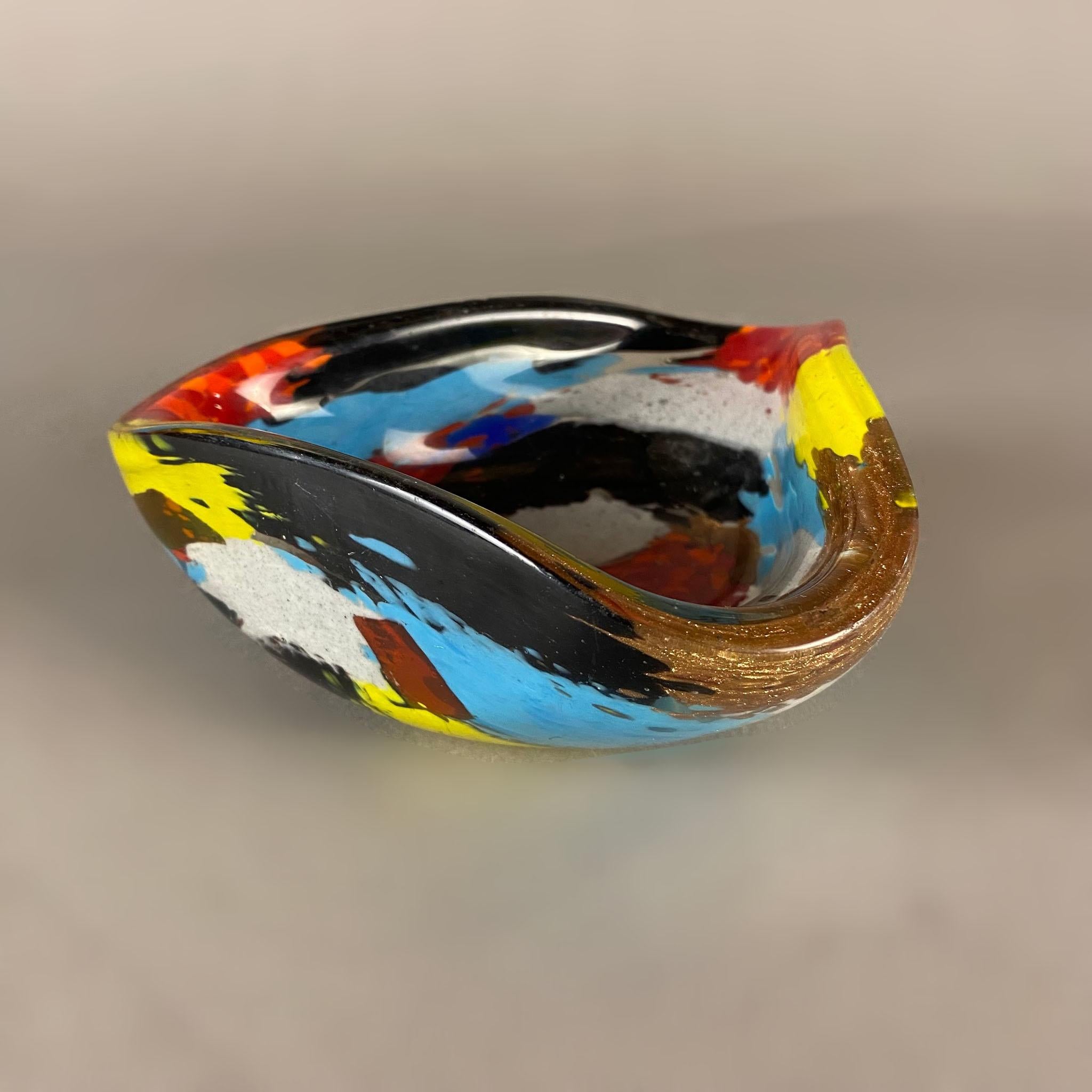 Coupe en verre soufflé de Murano datant des années 1950 et appartenant à la collection Oriente de Dino Martens pour Aureliano Toso. Le bol multicolore a une forme triangulaire arrondie et présente des applications de cuivre sur tout son corps.