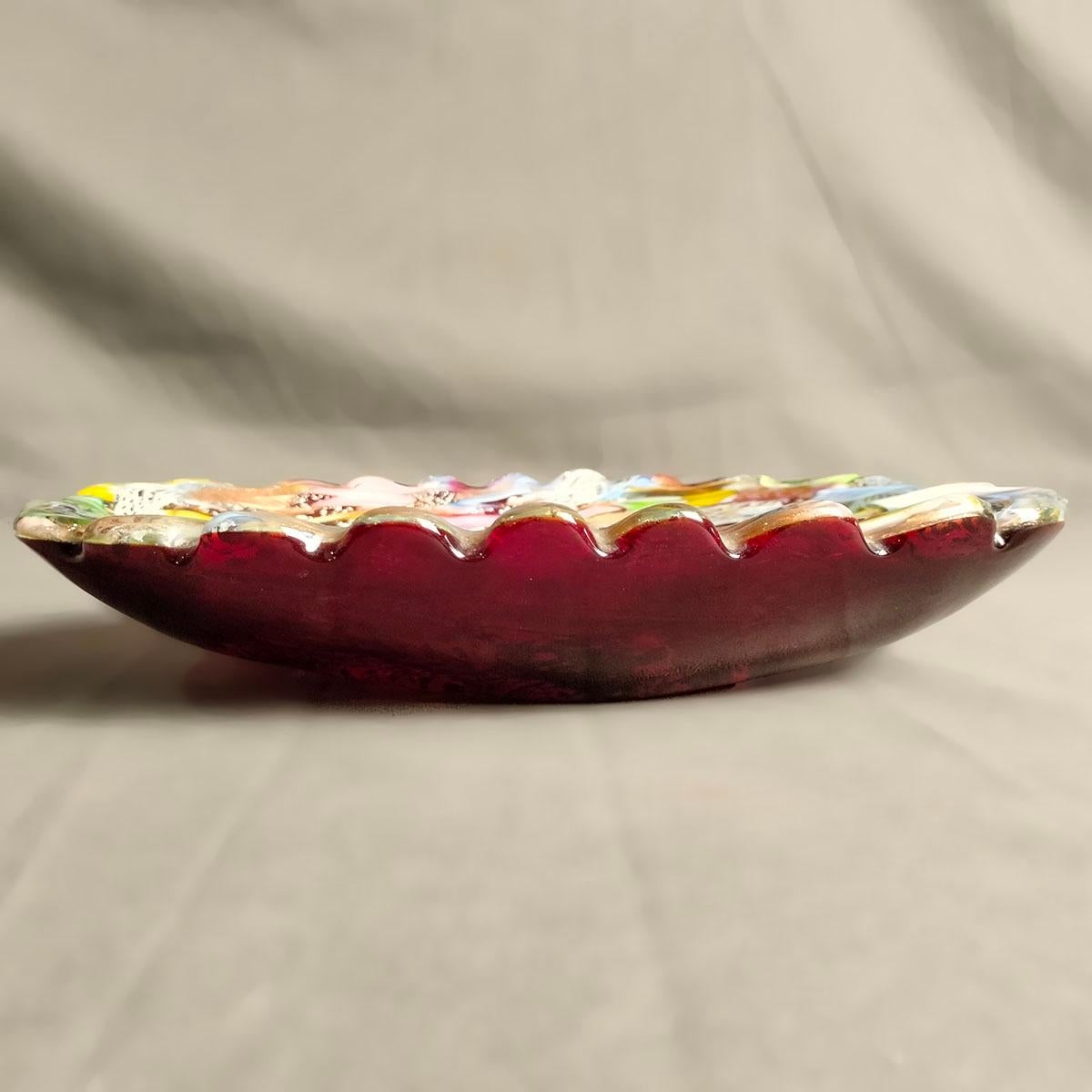 Eine italienische Schale aus mundgeblasenem Murano-Glas aus den 1950er Jahren von Dino Martens. Die mehrfarbige Schale hat eine ovale Form mit einem gewellten Rand und ist mit Silberapplikationen im Murano-Design versehen.

Corrado 