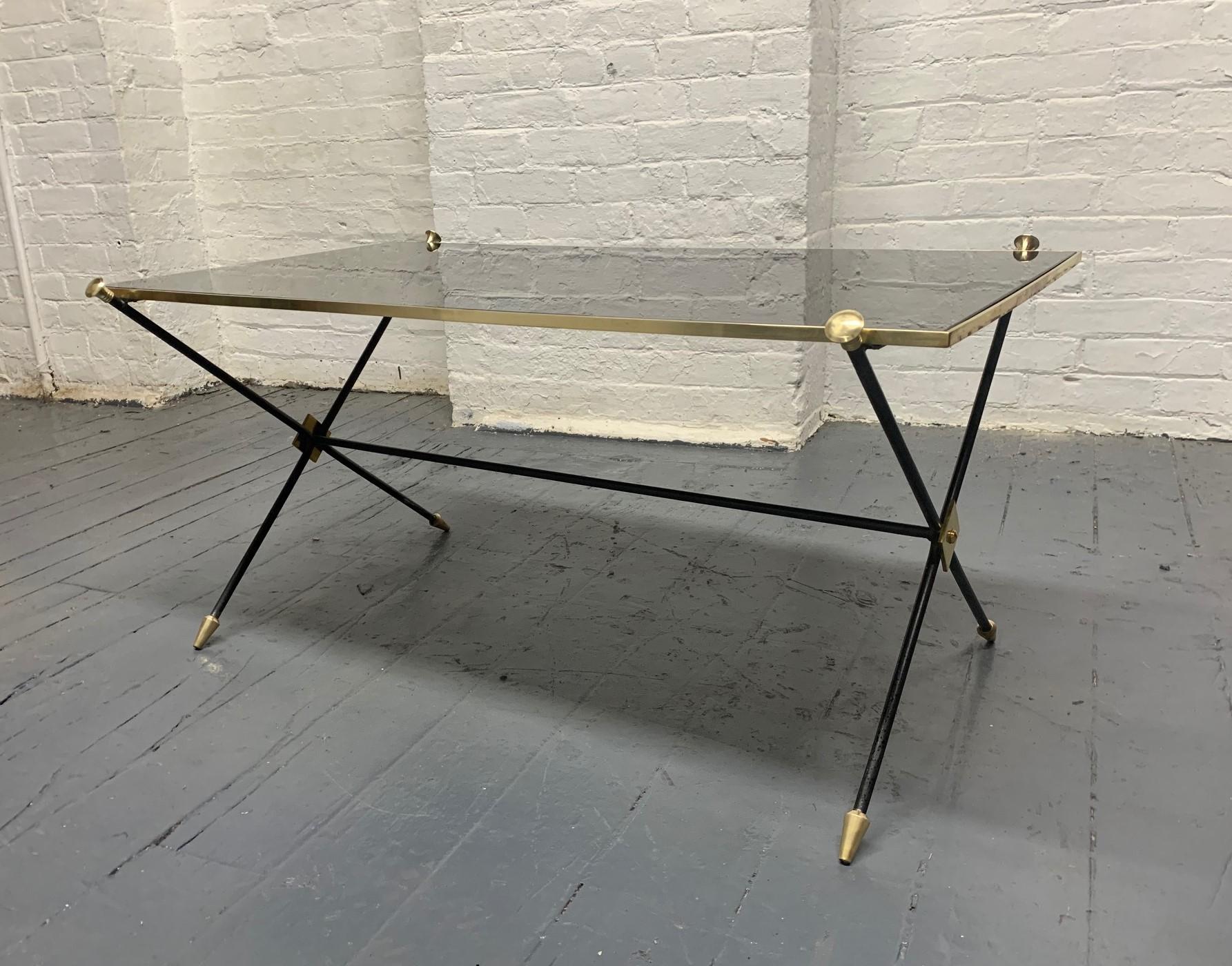 1950s Directoire style iron and brass trim coffee table. Has a smoked glass inserted to the top and arrow formed leg.