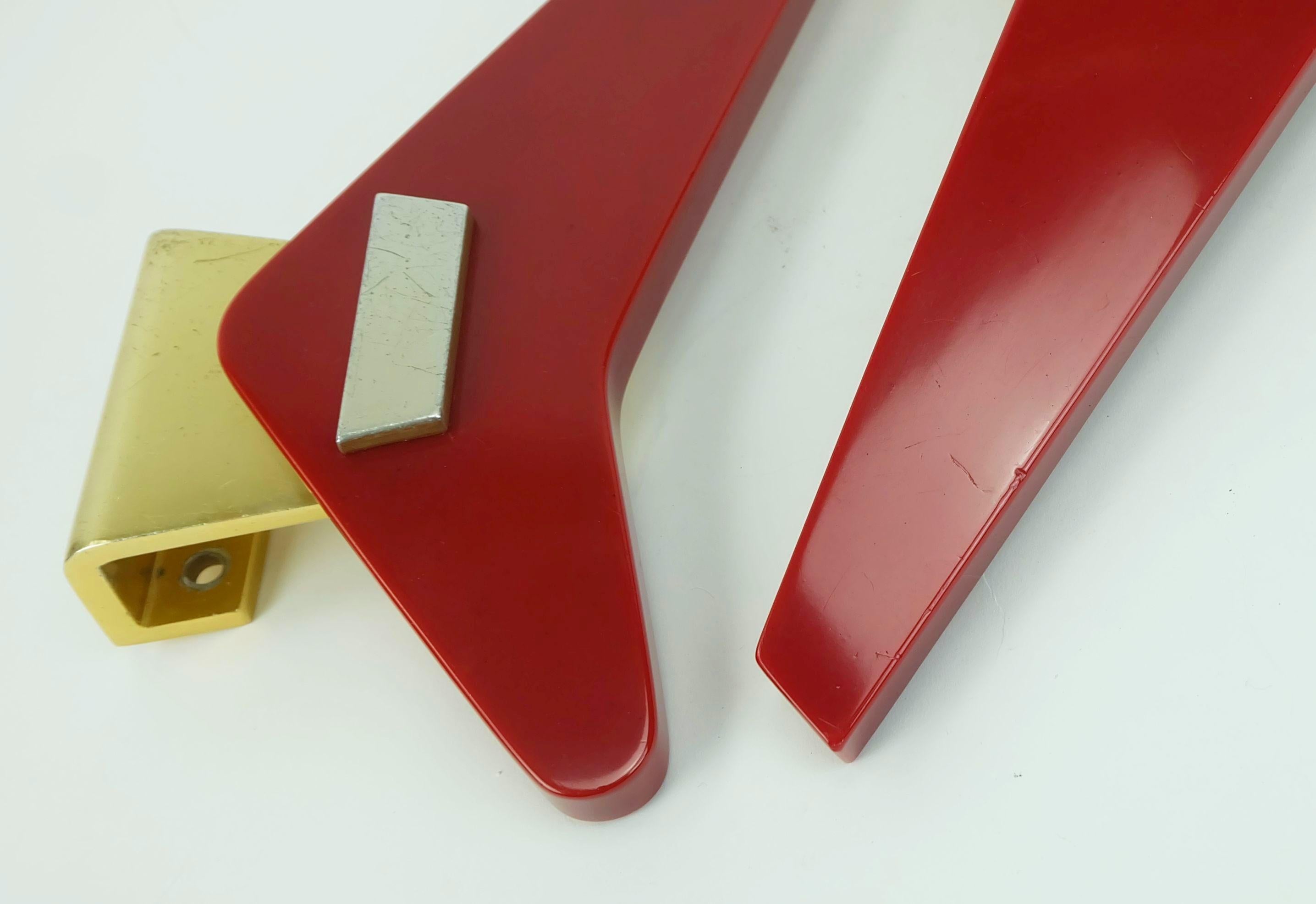 A pair of highly decorative door handles from the 1950s with a striking streamlined design. Made of red Bakelite and gold-colored anodized aluminum. 

Dimensions in cm: 
Height 30.5 cm, width 18 cm, depth 6.5 cm. Distance between drill holes 4.5