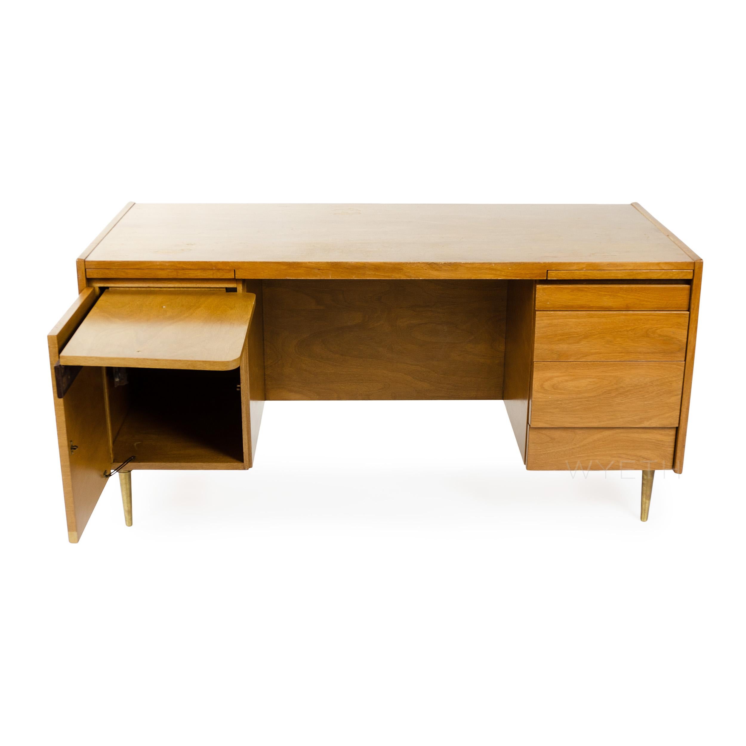 An elegant and finely proportioned bleached walnut double pedestal desk with ample storage floating on dowel-shaped brass legs.