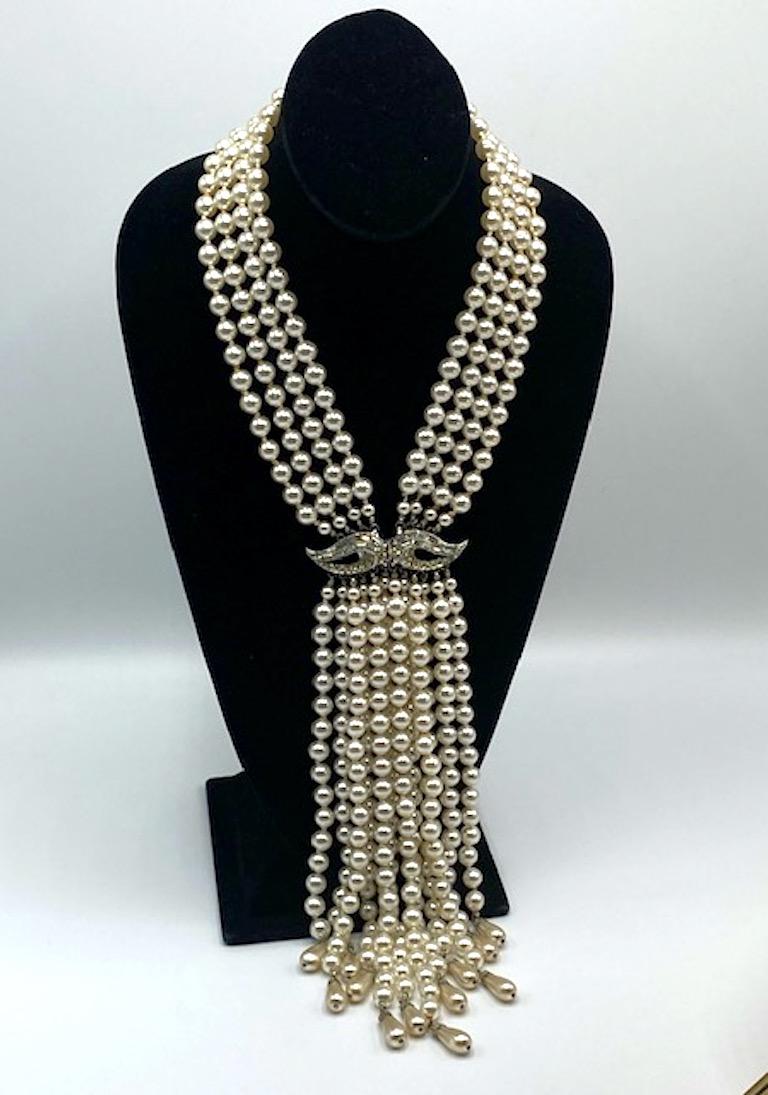 A stunning and dramatic unsigned vintage pearl waterfall necklace from the late 1950s to the early 1960s. Four strands of individually knotted faux pearls 18 to 19 inches in length come together at a a horizontal clasp set with round and baguette