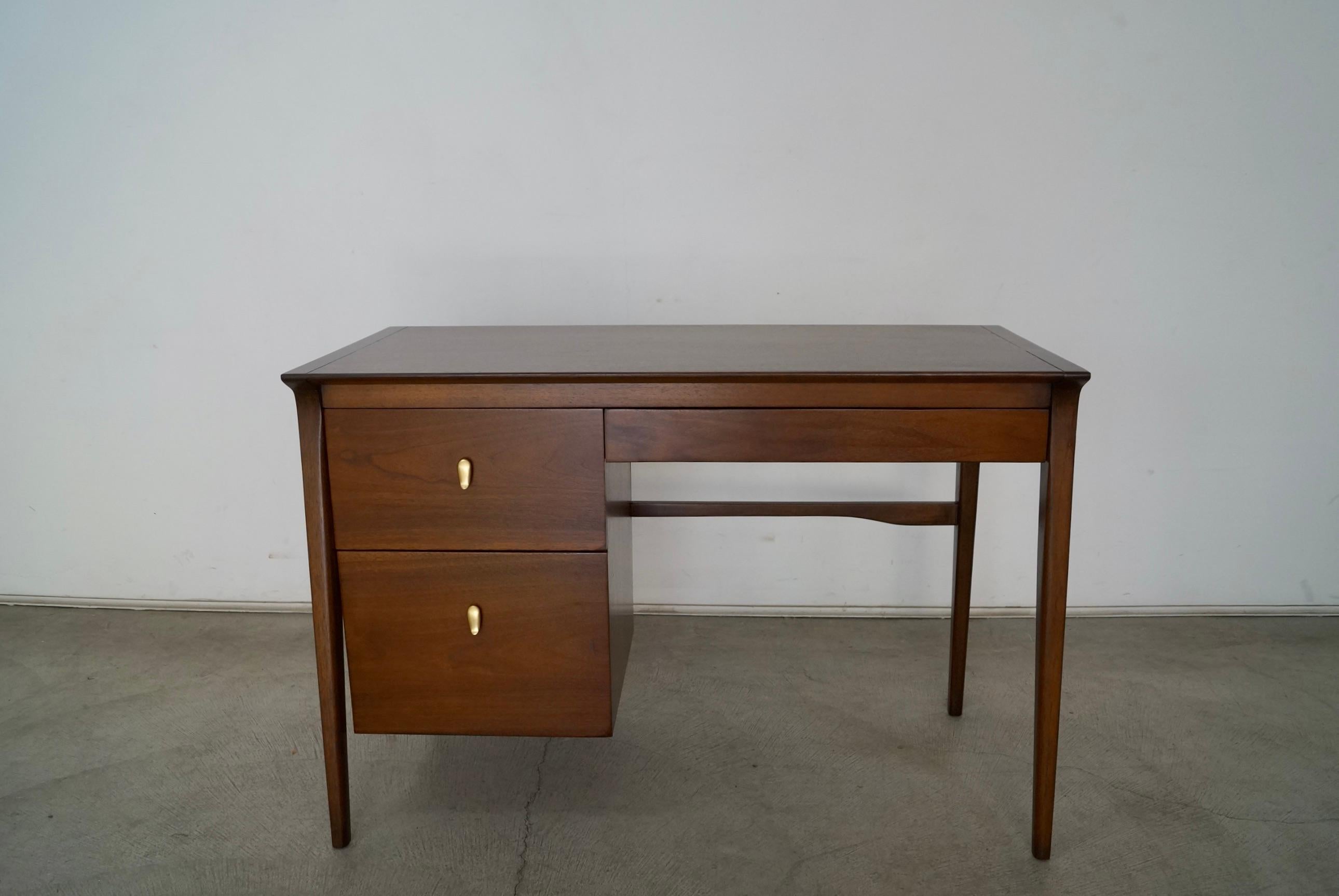 Vintage Mid-Century Modern desk for sale. Designed by John Van Koert for Drexel, and part of the collectible Profile series. It has been beautifully refinished in walnut, and has the original brass knobs. It has three drawers dovetailed on both