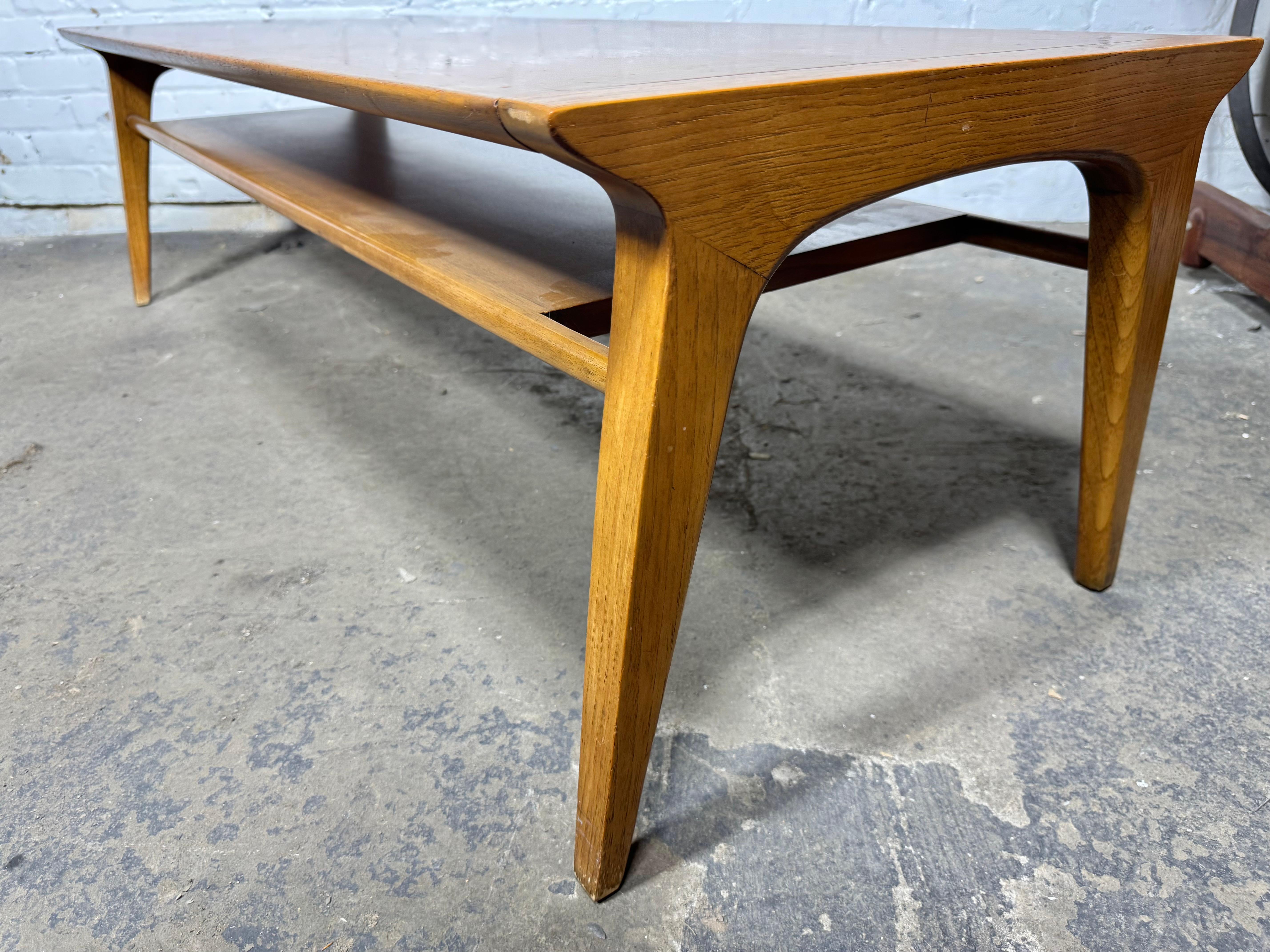 Drexel Profile walnut and pecan cocktail or coffee table, model K92, circa 1950s. The rectangular low profile and streamlined top features a distinct recessed under-shelf raised on angled square tapered legs. The slim space between the two-tiers