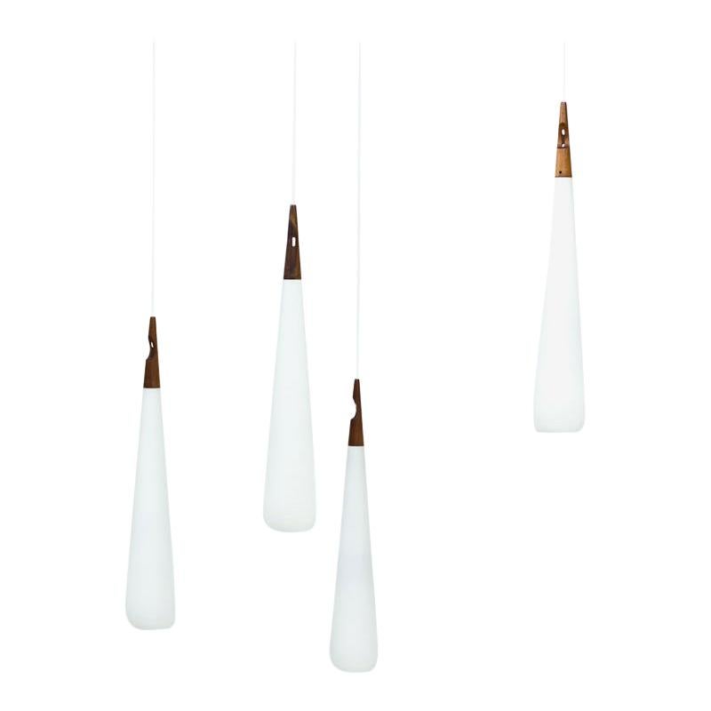“Droppe” pendant lamps designed by Uno & Östen Kristiansson.
Manufactured by their own company Luxus at Vittsjö in Sweden during the 1950s. 
Long drop shaped opaline glass with teak fitting. New electricity.