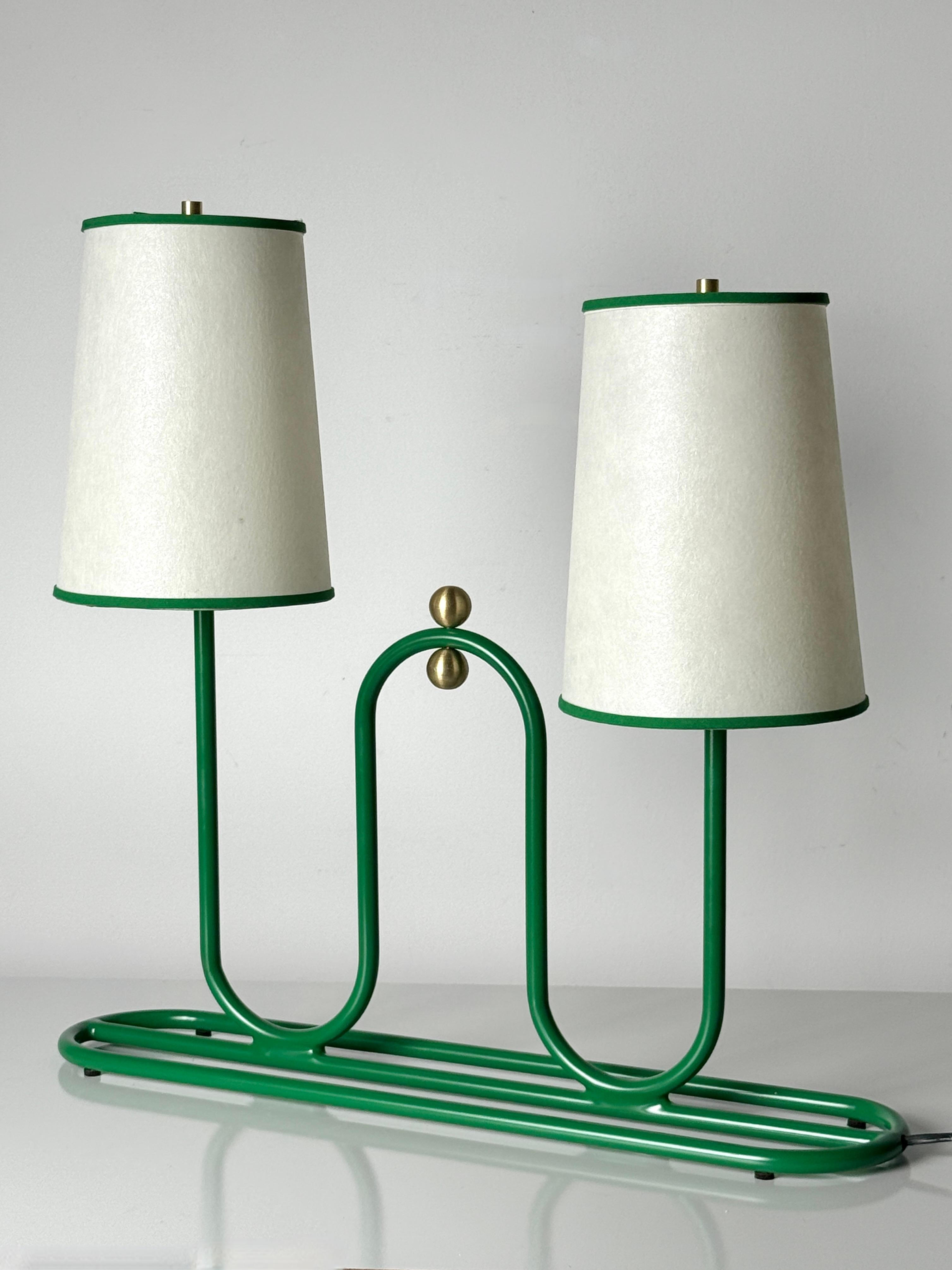 Exquisite table or desk lamp in the manner of Jean Royère circa 1950s

Loop design tubular metal base in vivid green with center brass orb finials 
Supporting two conical shades poised at varied height

The lamp has been restored and outfitted with