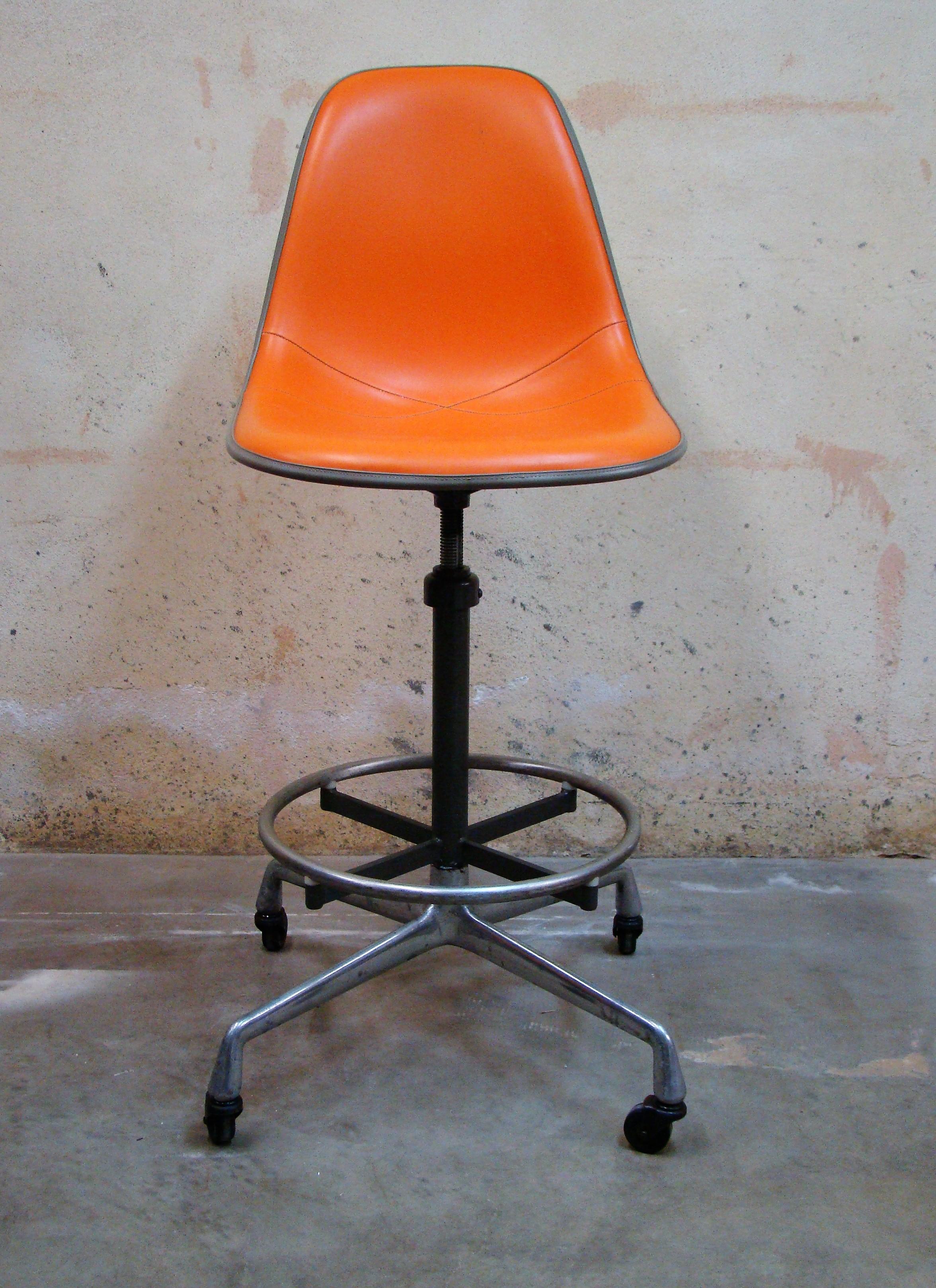 Original 1970s drafting stool designed by Charles and Ray Eames for Herman Miller (USA) with a striking orange upholstered white fiberglass side shell seat and 'Aluminum Group' swivel drafting stool base, adjustable in height with hard rubber