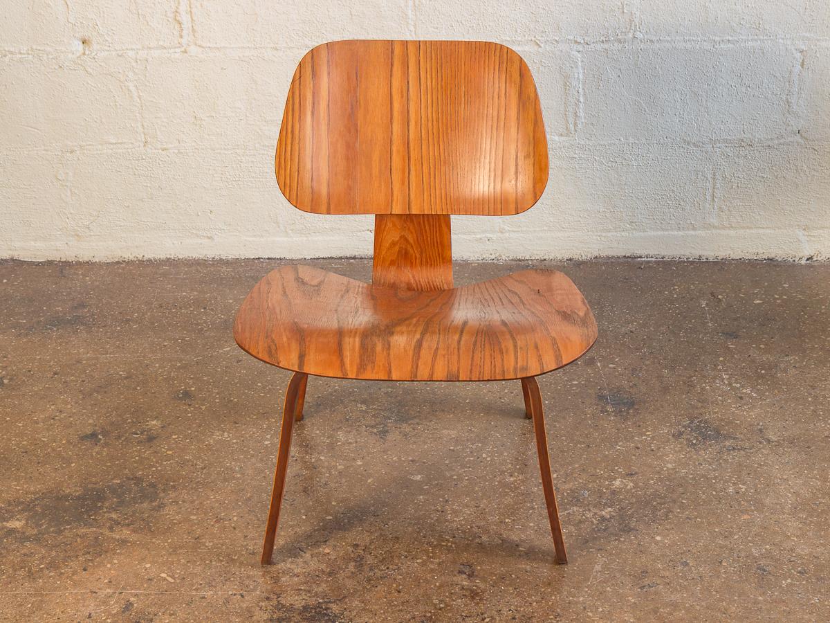 Stunning molded plywood ash LCW by Charles and Ray Eames for Herman Miller. Our 1950s example adorns a distinctive wood grain, which follows every bend and curve on the surface of the chair and is incredible. The low-slung form is strong and