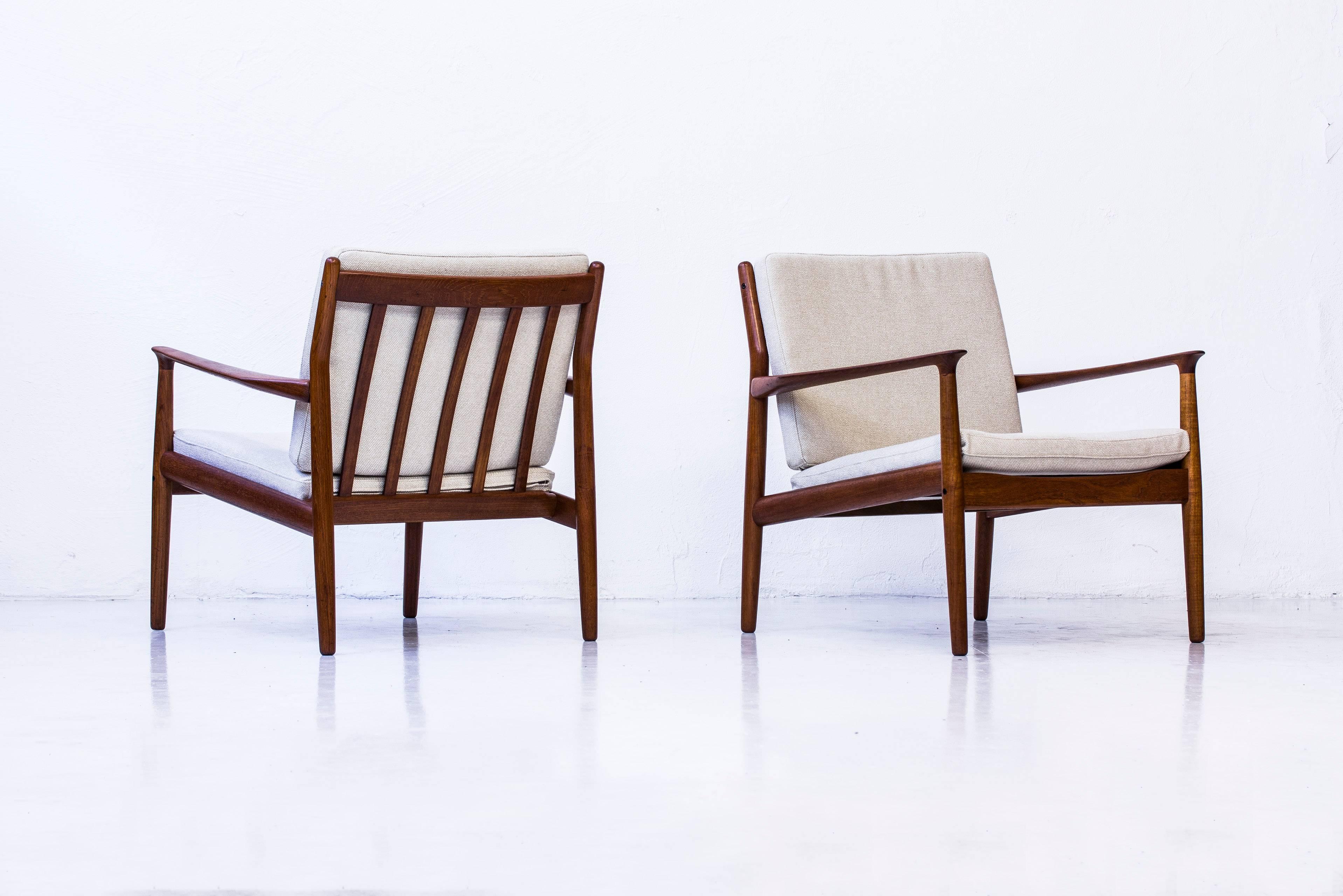 Pair of easy chairs designed by Grete Jalk. Produced in Denmark during the 1950s by Glostrup Møbelfabrik. Made from solid Bangkok teak wood with reupholstered cushions in 