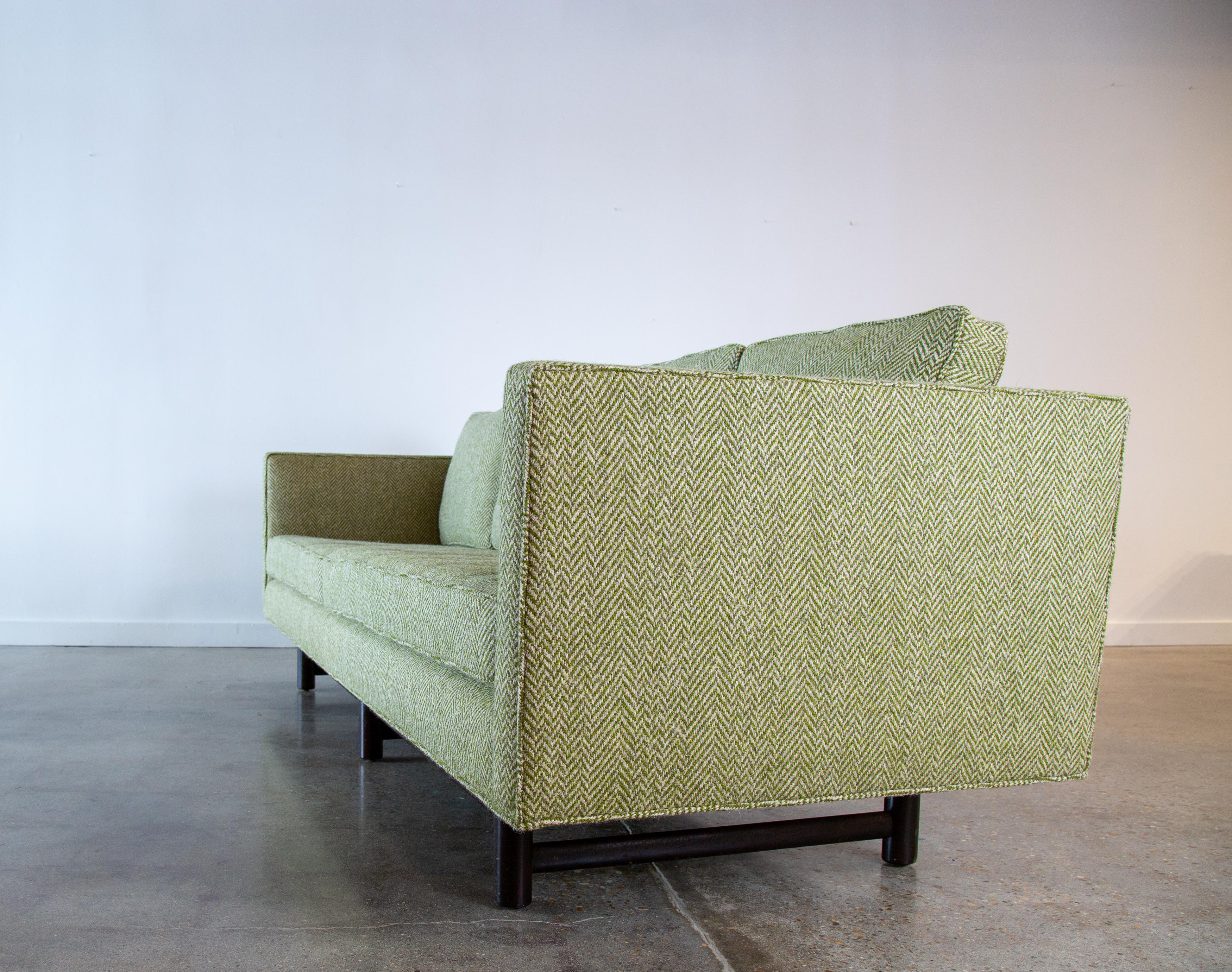 A 1950s tuxedo, even arm sofa by Edward Wormley for Dunbar, model 5138. The sofa floats on a solid mahogany base and is upholstered with new foam and a high end green wool fabric from Vladimir Kagan’s personal archive of fabrics.  A great green and