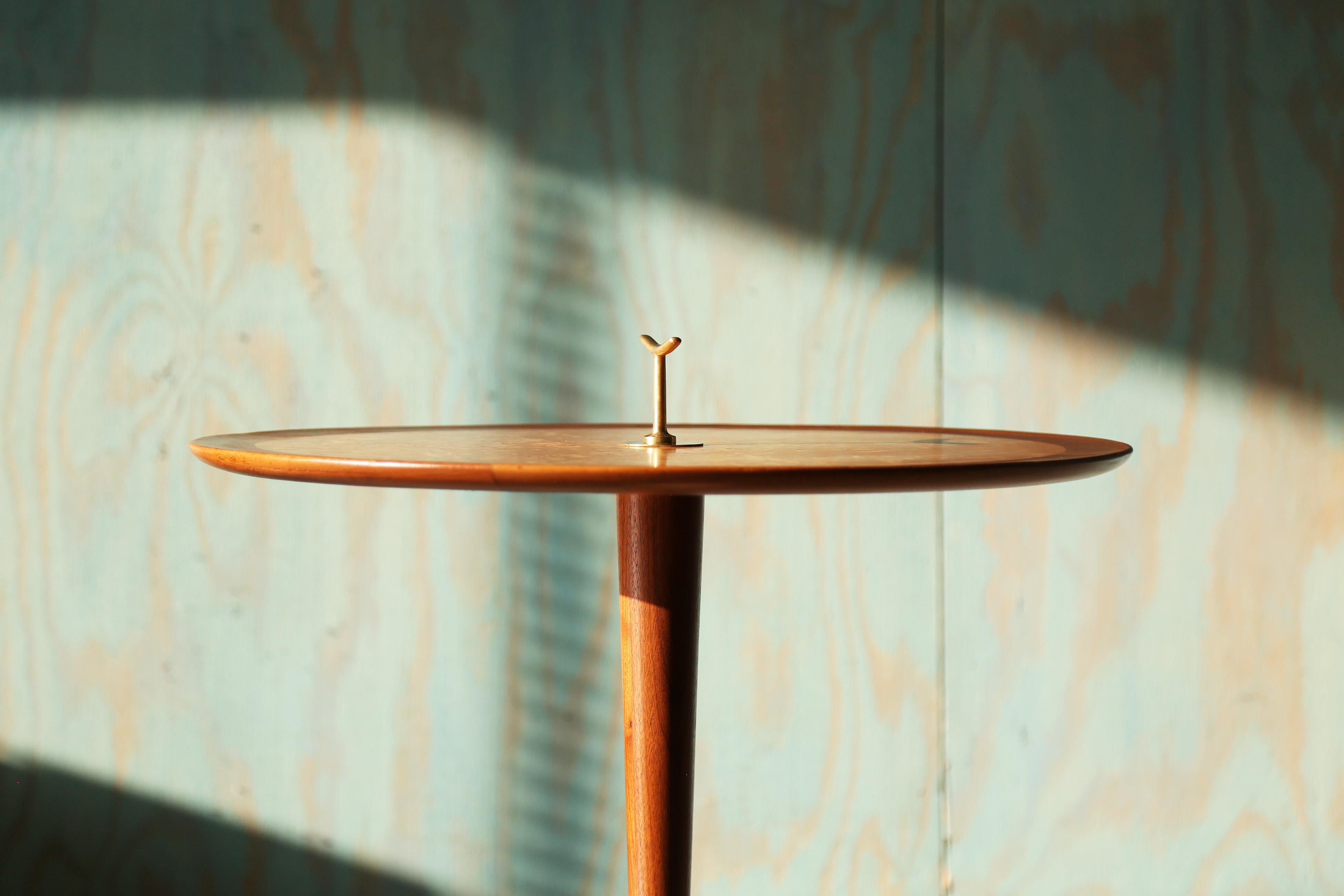 An elegant snack table designed by Edward Wormley for Dunbar.  The model 4856 table consisting of a solid brass tripod base, solid walnut stem, and birch burl veneer top.  The solid brass handle adorns the top and allows for picking up the table