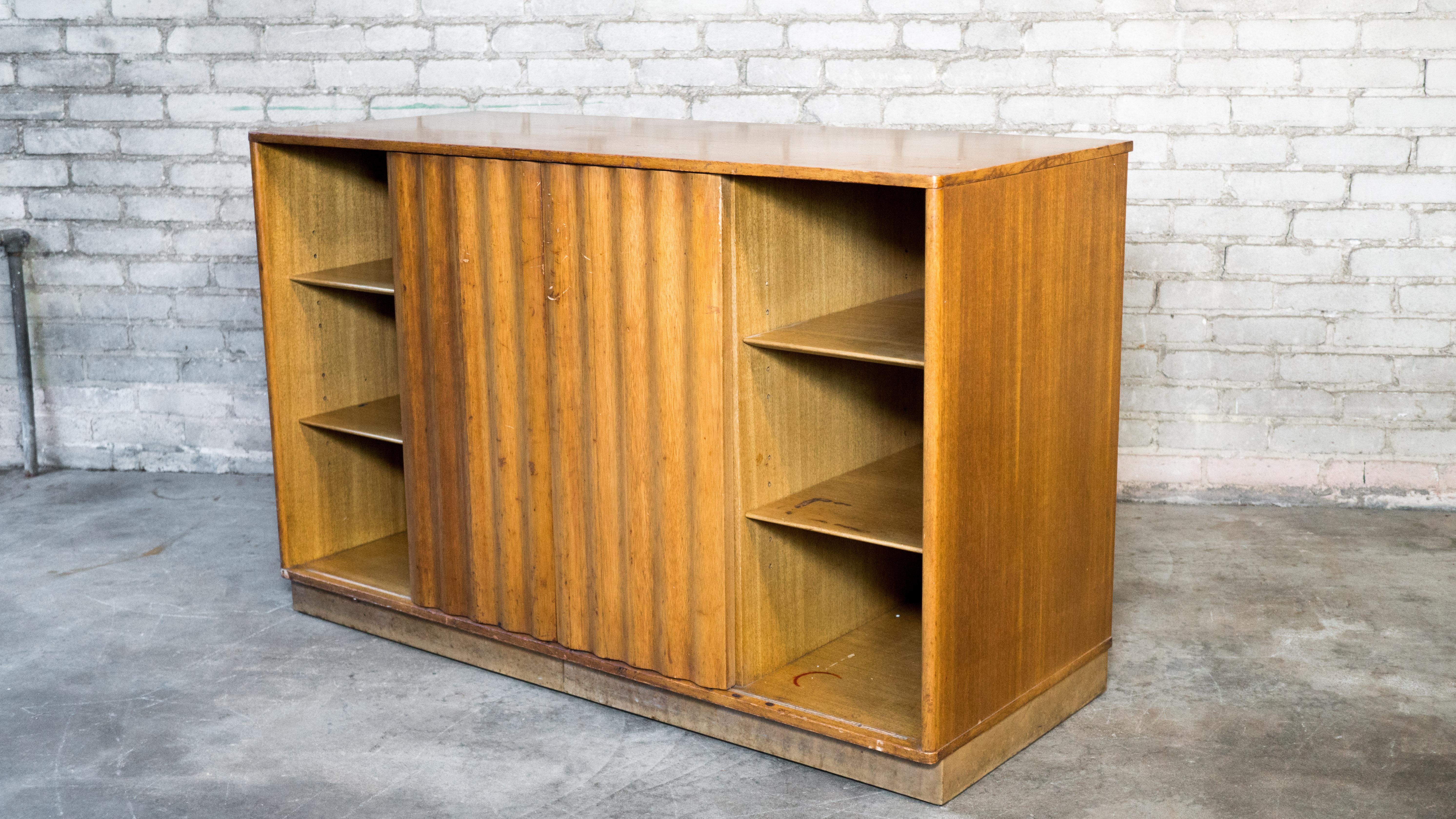 Edward Wormely for Dunbar credenza or sideboard, circa 1950s. Presented in mahogany, showing lovely woodgrain details. Wave form sliding doors flank the center drawers. Beautiful craftsmanship. Dovetail joints, adjustable selves. Leather wrapped