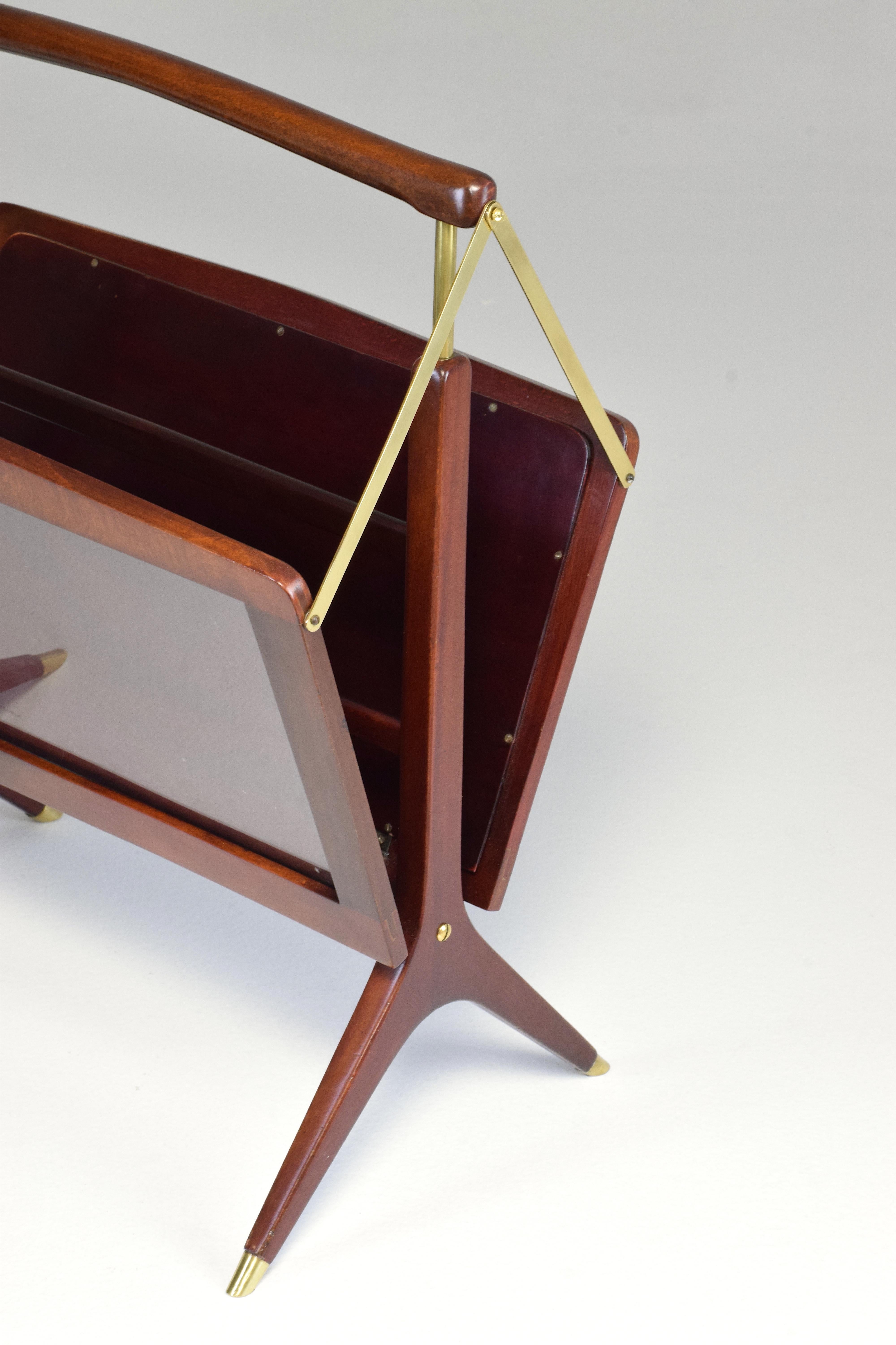 A 20th-century vintage foldable magazine and newspaper holder in the style of Italian designer Ico Parisi. Made in Italy circa the 1970's, this decorative stand is composed of re-finished wood, elegant brass details and see-through glass panels. 
A