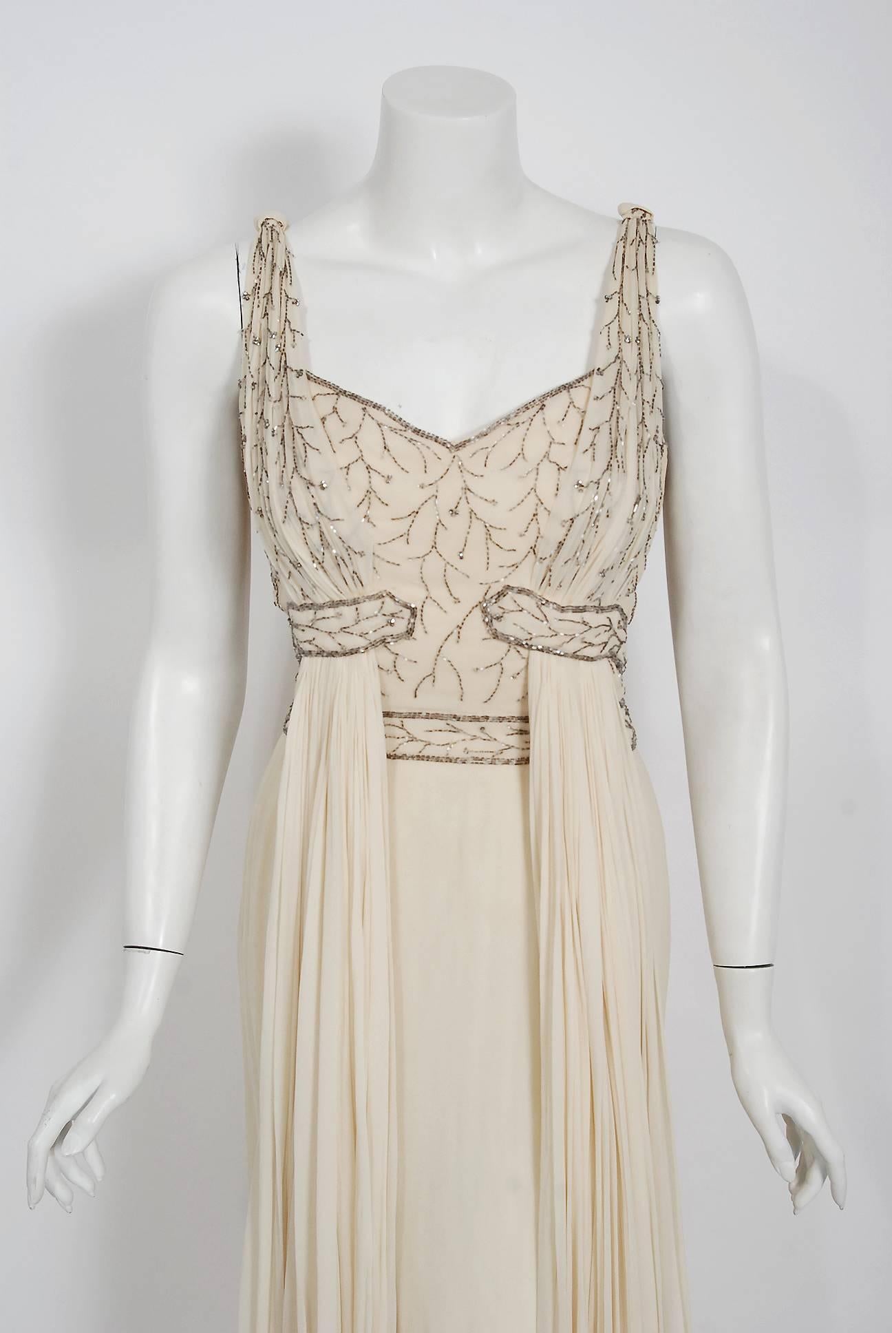 Breathtaking ivory silk-chiffon glass beaded dress created by Italian designer Fernando Sarmi when he was head designer for Elizabeth Arden during the 1950's. Ferdinando Sarmi expressed interest in fashion during his youth but was discouraged from