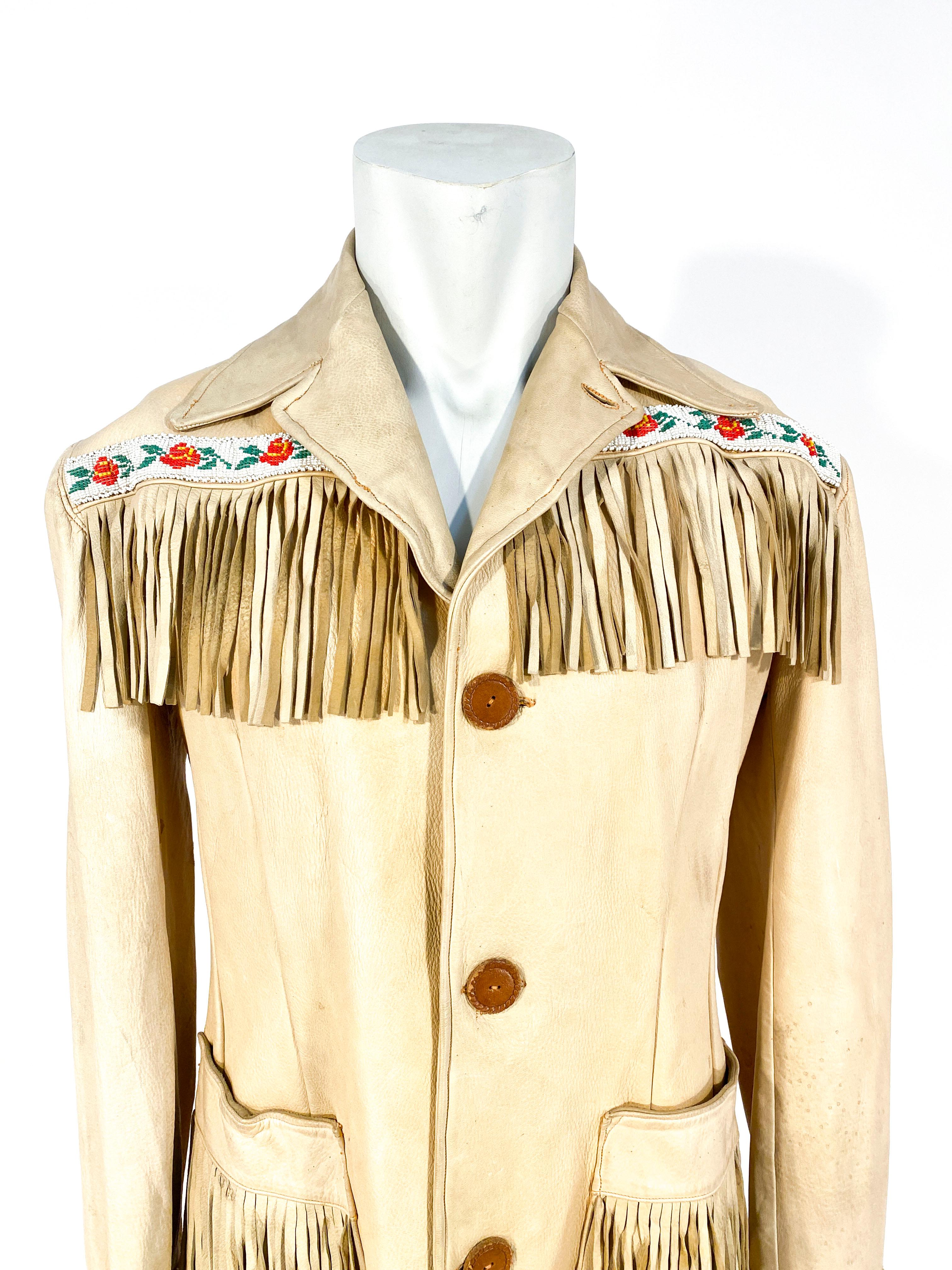 1950s elk hide handmade jacket with fringe along the hem, pockets, sleeves, and across the back. The face of the jacket is decorated with handmade leather buttons and beaded trim on both cuffs.