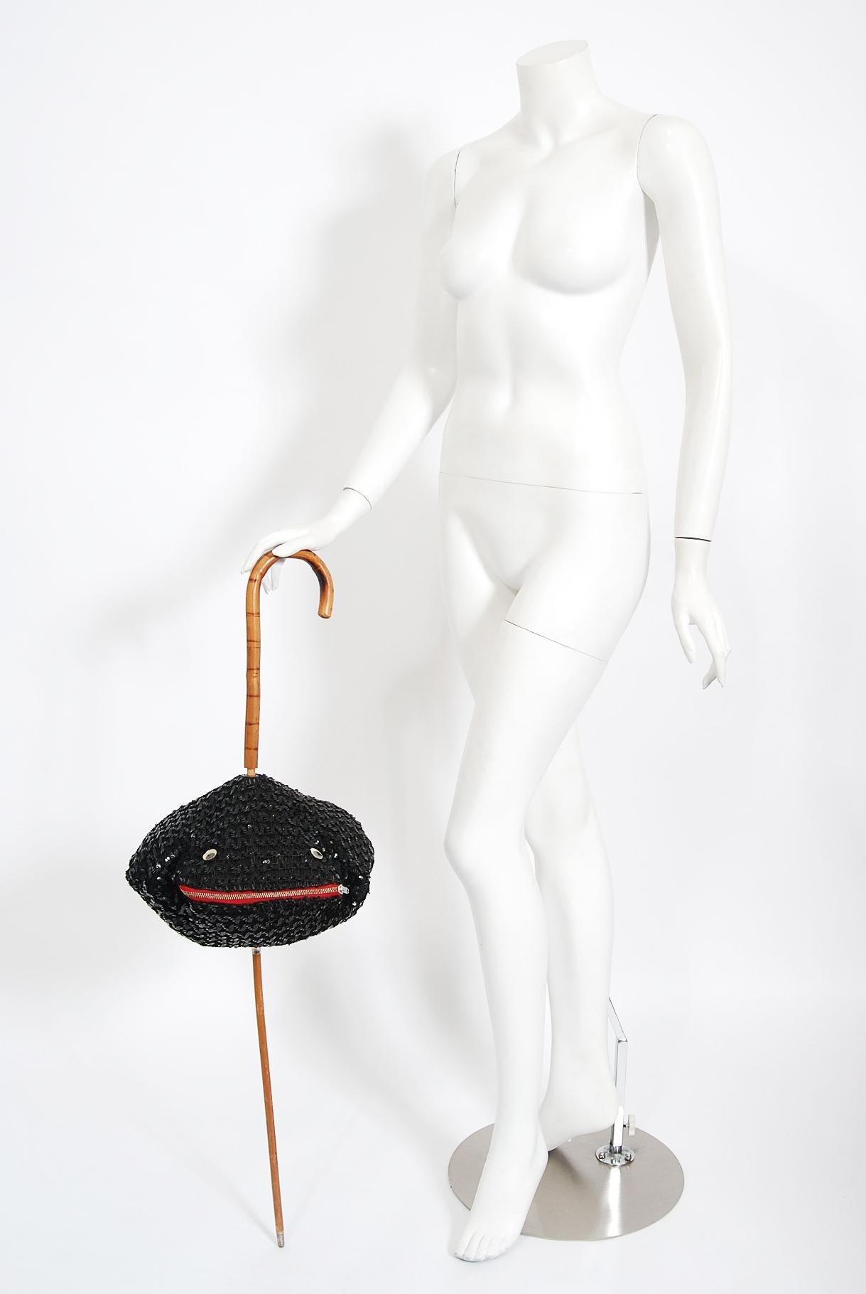 A highly coveted and incredibly unique Elsa Schiaparelli sequin blowfish cane purse dating back to the early 1950's. Fashioned from rich red vinyl bubble covered in black knit with serpentine rows of black sequins. A whimsical blowfish face