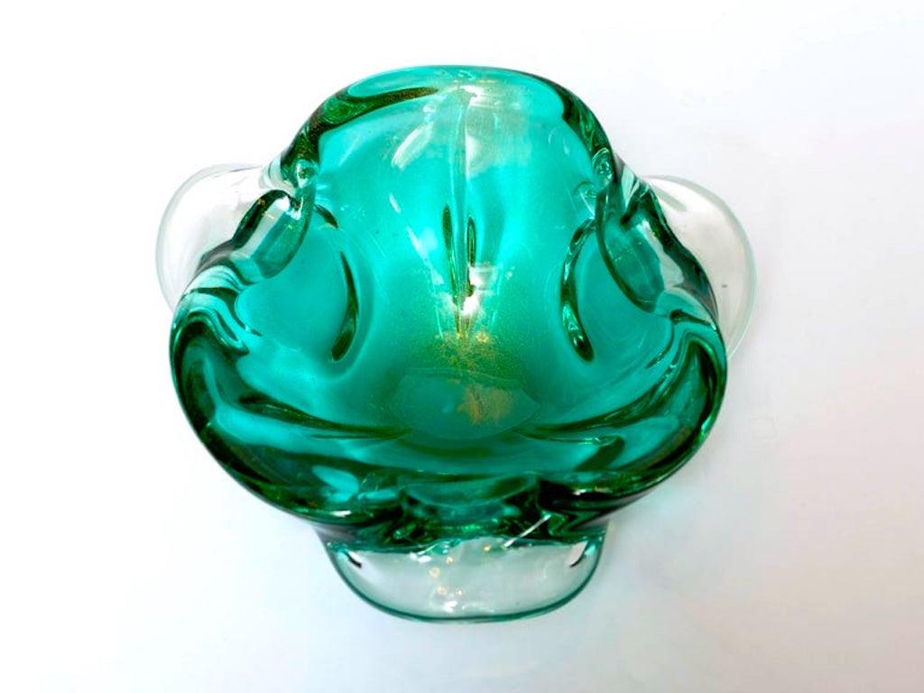 Mid-Century Modern glass bowl or ashtray with organic form. Comprised of hand blown Murano glass in hues of emerald green with gold fleck details. Beautiful from every angle, the bowl features pinched rim design with trilateral winged sides.