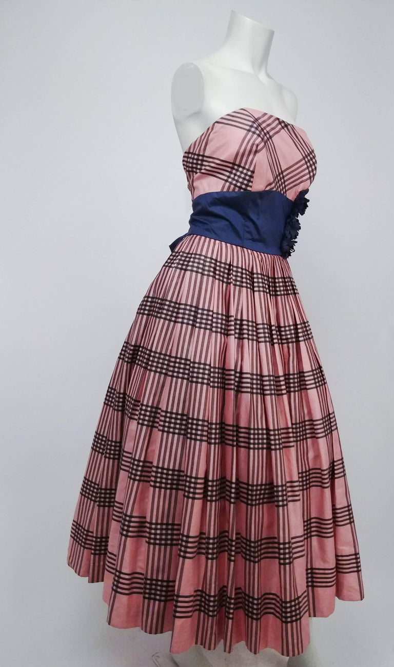 1950s Emma Domb Pink Plaid Party Dress. Navy blue waist sash punctuated with flowers at size, bow at back. Strapless neckline, boned bodice. Built-in tulle crinoline. 