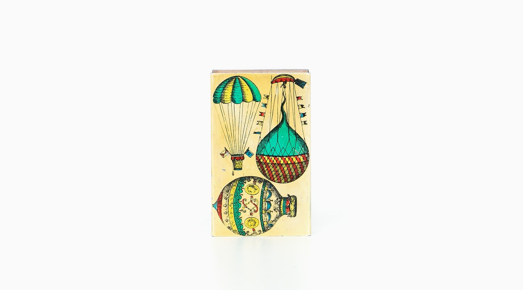 Wonderful and extraordinary vintage Fornasetti box. It has a enameled metal cover with Fornasetti's iconic graphics, showing three hot air balloons in vivid colors. The inner compartment is in wood. The bottom is mint green felt. Manufactured by