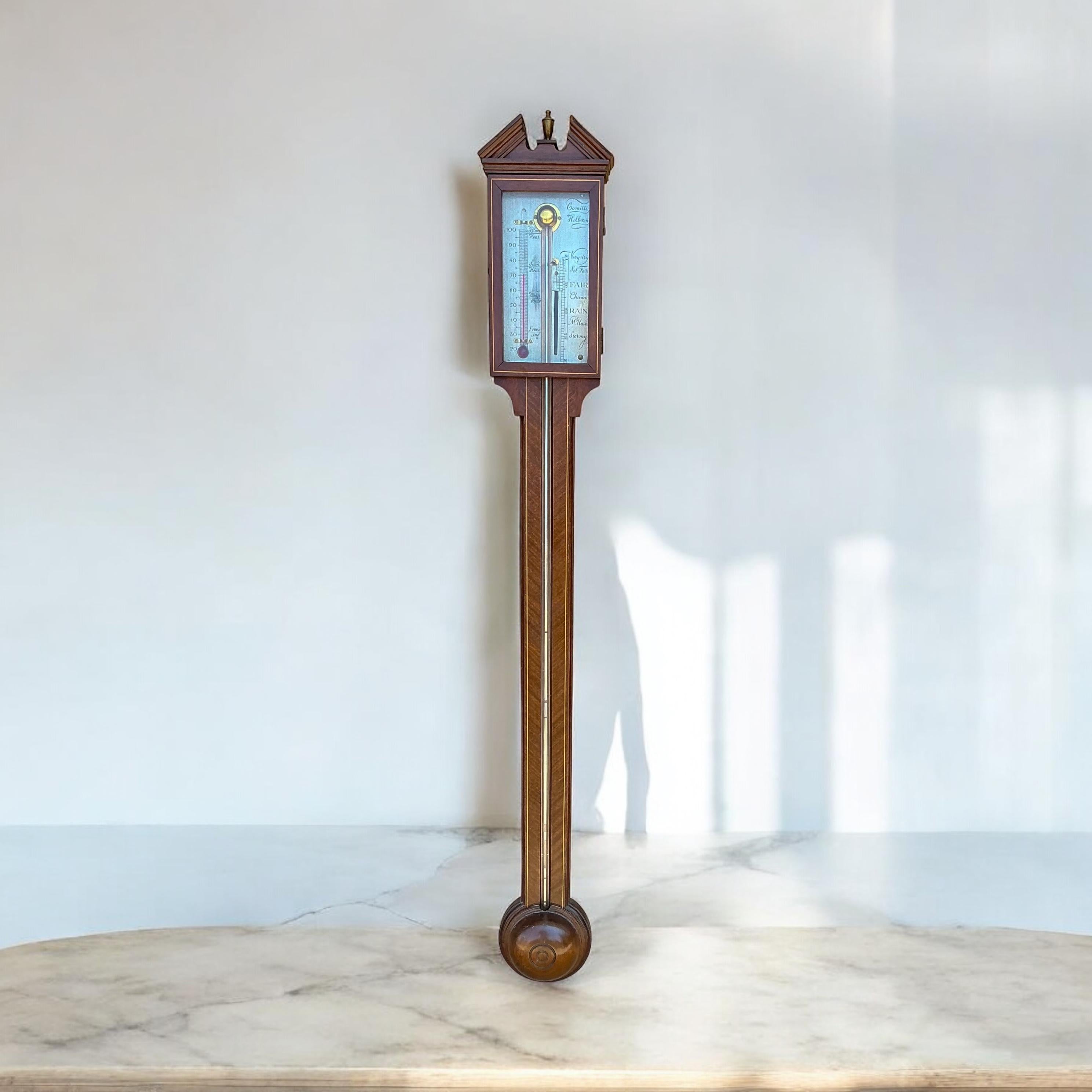 This is an English Georgian style mahogany stick barometer hand crafted by Abercrombie & Fitch. The mahogany has a band of inlaid satinwood. The glass front opens via a tiny hinge and hook. It is marked and in very good condition. It is estimated to
