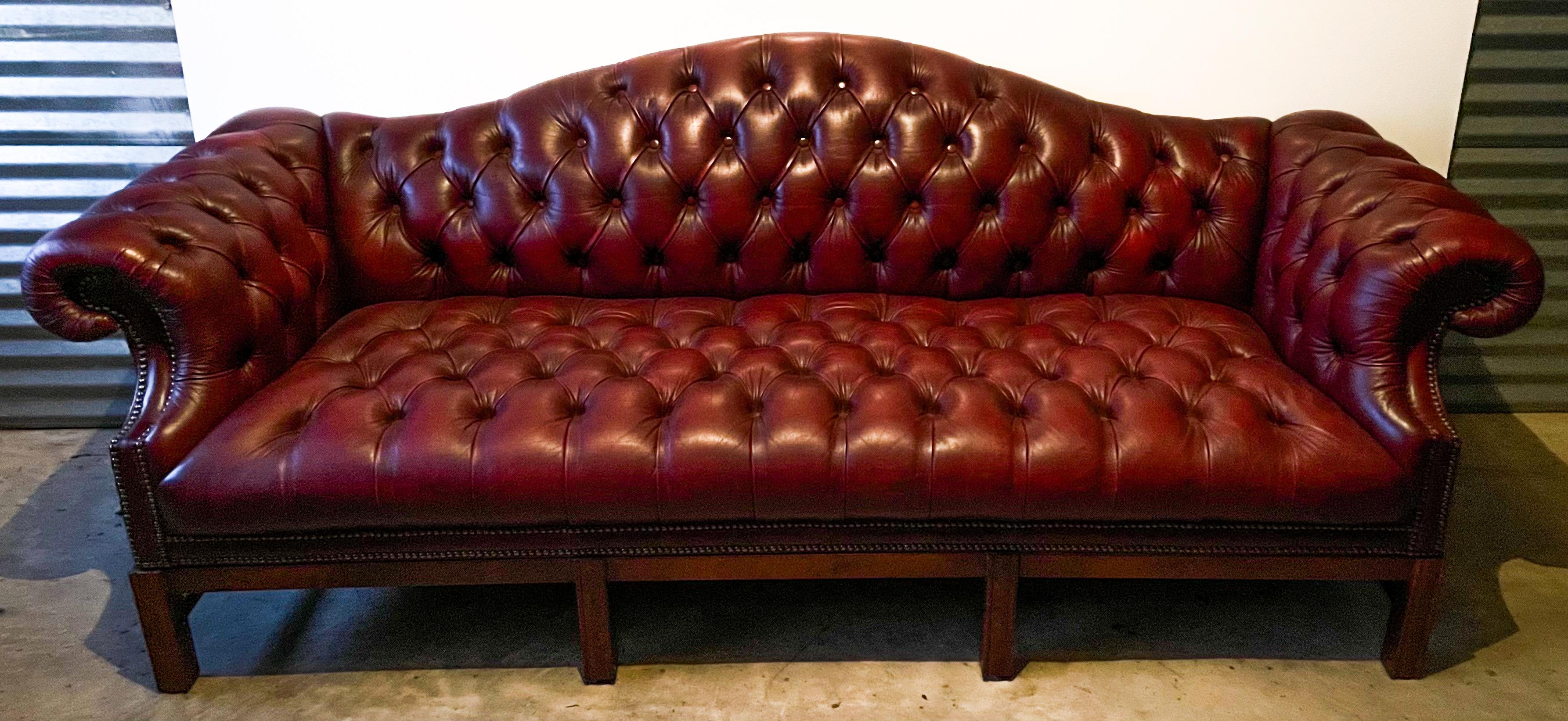 This is a wonderful 1950s burgundy / garnet English tufted leather chesterfield camelback sofa. The frame is mahogany, and it is in very good condition. It is unmarked.