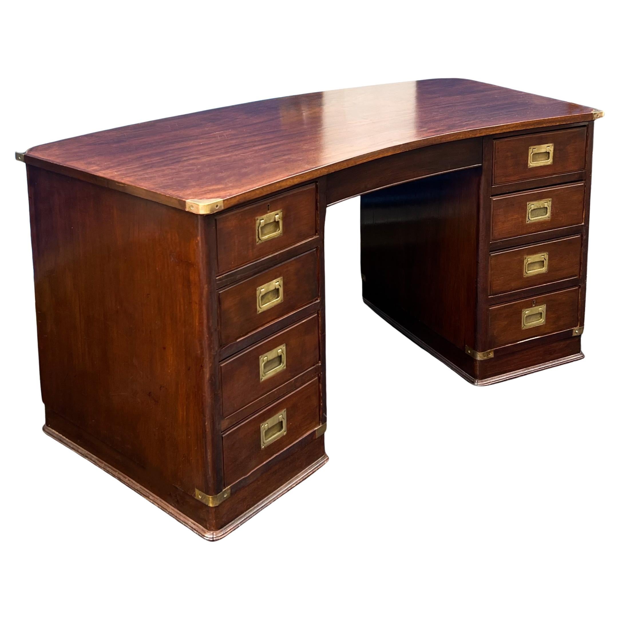 This is a 1950s English mahogany and brass campaign style desk. It is marked with a back brass plate. The drawers have dovetail construction. It has a subtle curving to the shape.

My shipping is for the Continental US only and running two to five