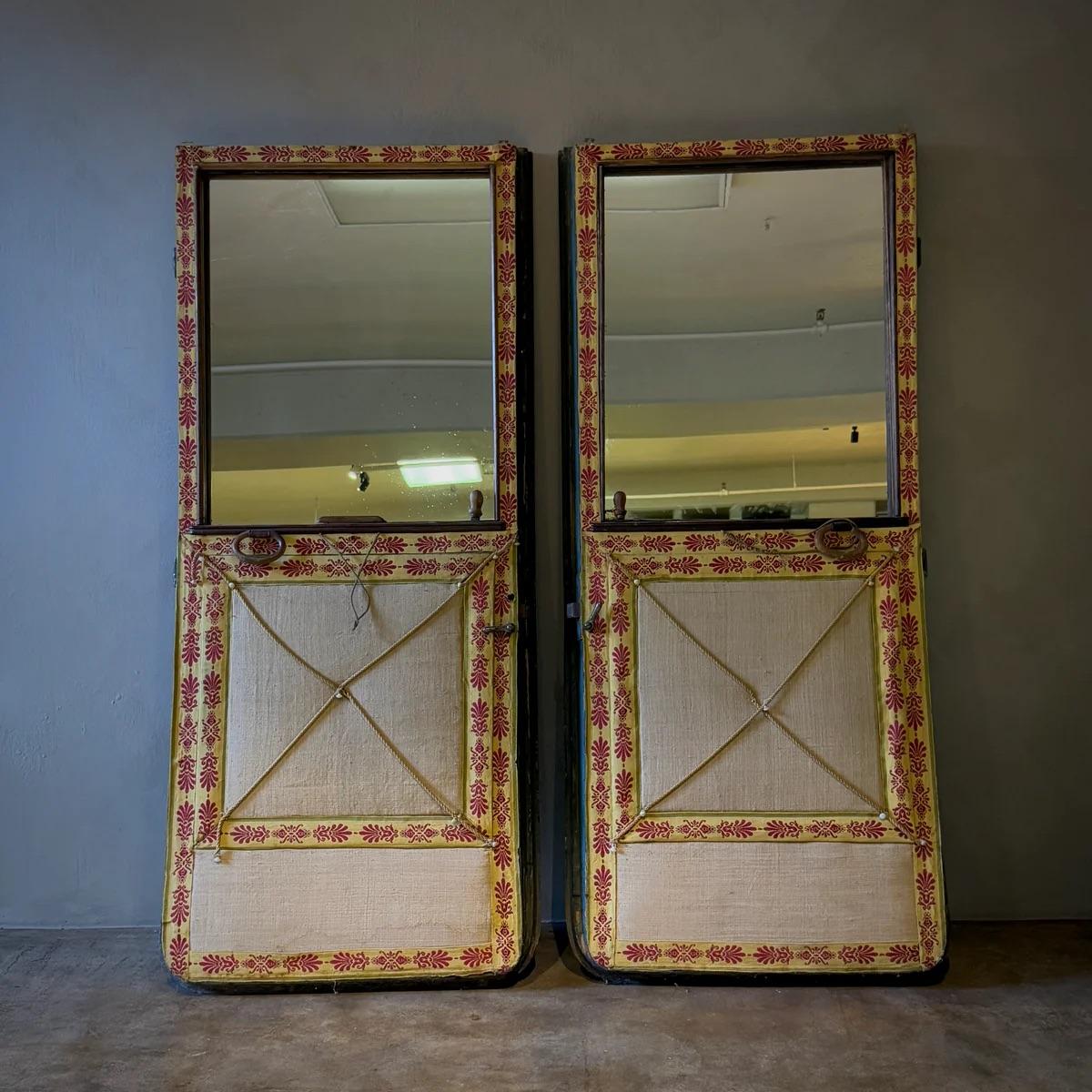 Questa splendida coppia di porte di carrozze inglesi della metà del secolo scorso è stata riutilizzata in modo innovativo, con le finestre trasformate in specchi. Conservando la vernice celadon profonda originale, ogni porta presenta una patina