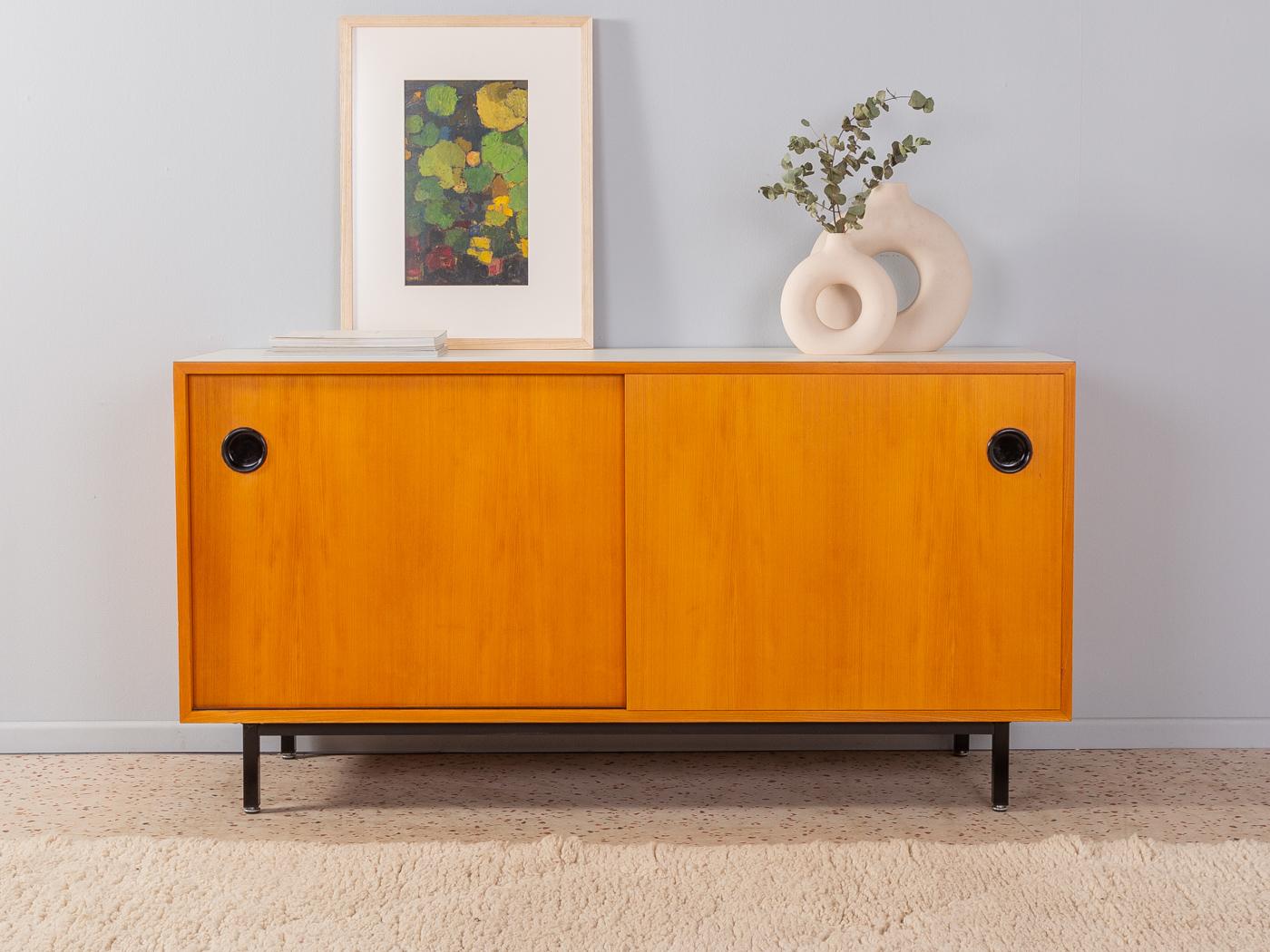 Rare sideboard from the 1950s by Erich Stratmann for Oldenburger Möbelwerkstätten. Corpus in ash veneer with two sliding doors, two shelves and new squared steel feet in black. The top is coated with creamy white formica.

Quality Features:
