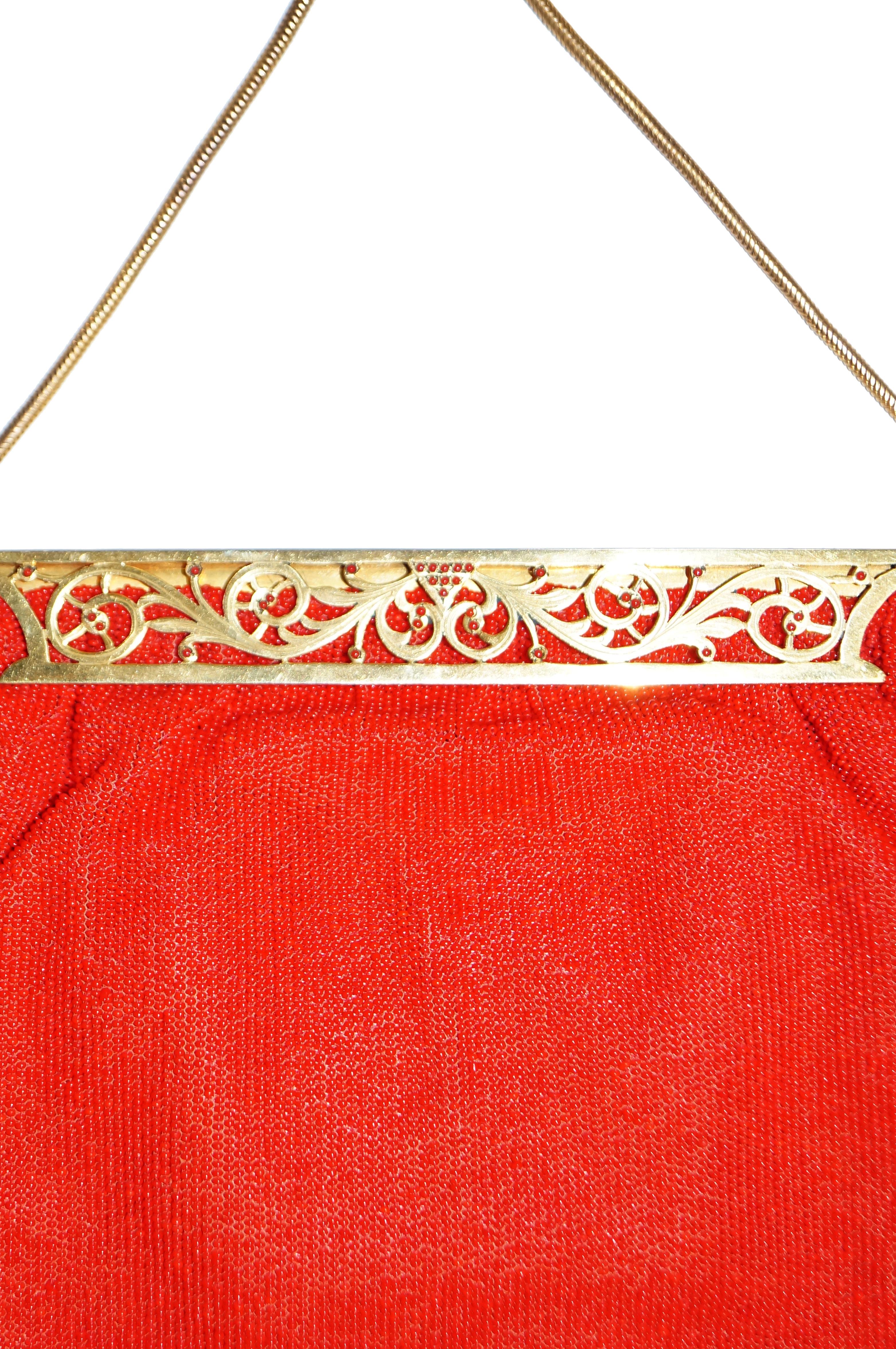 Brilliant red mid century handbag by Eugene Elias Paris. The handbag is shaped like a trapezoid, with a fully beaded, shimmery red exterior, and with a gold - tinged brass frame. The frame features elegant art nouveau - like floral scrollwork. The