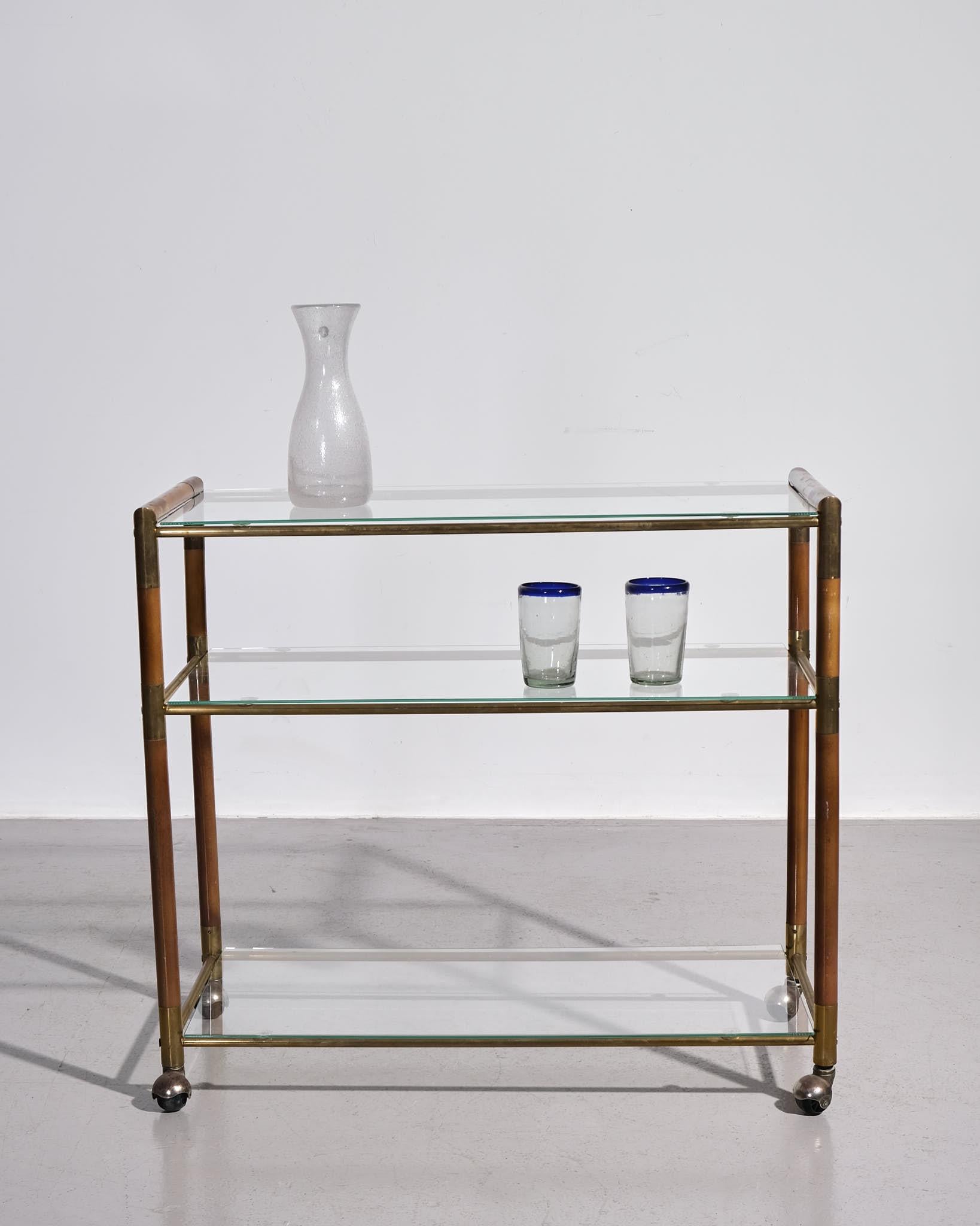 Un élégant chariot à boissons européen en verre, datant d'environ 1950. Cette élégante pièce du milieu du siècle présente un cadre en laiton poli et deux niveaux d'étagères en verre transparent, offrant à la fois style et fonctionnalité. Les