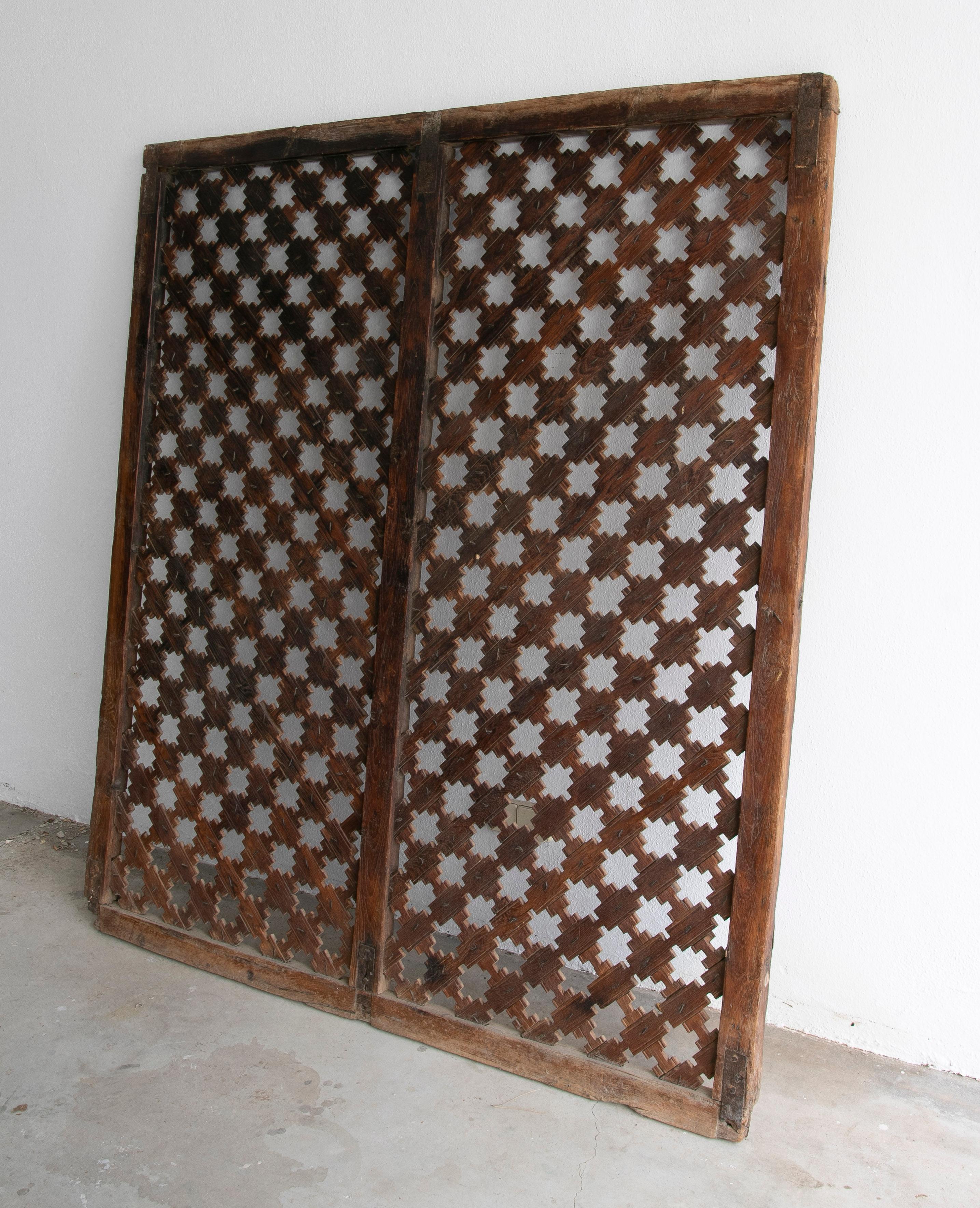 Vintage 1950s European wooden latticework screen with a geometric design created by crossing strips to form a grid and held with iron nails and reinforced corners.


