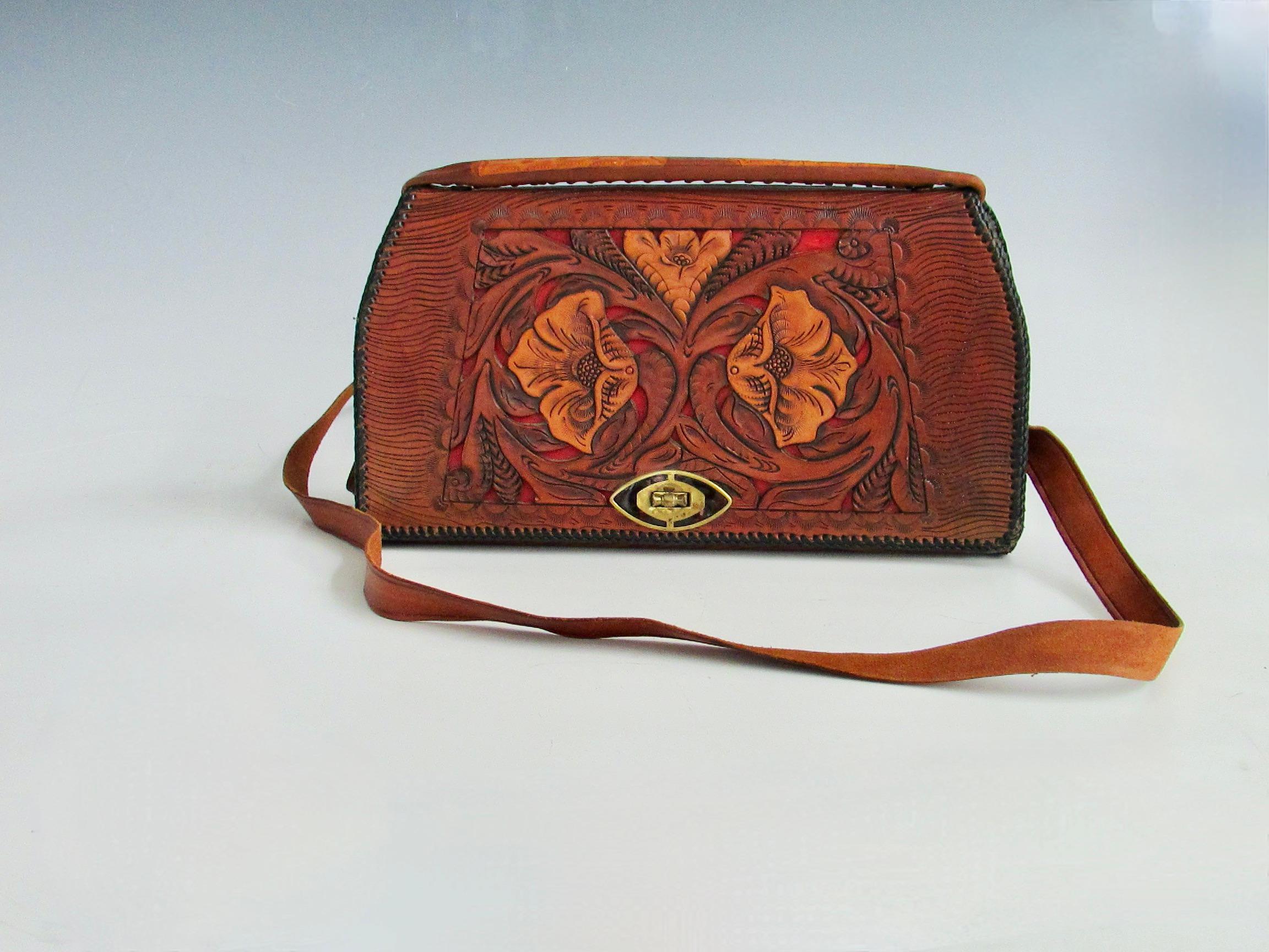 Nicely and highly tooled western theme leather purse . Decorated on both sides and the interior .  Open the flap to find red interior and equestrian embellishment . Wonderful condition throughout . No losses , strap and handle in fine condition . 