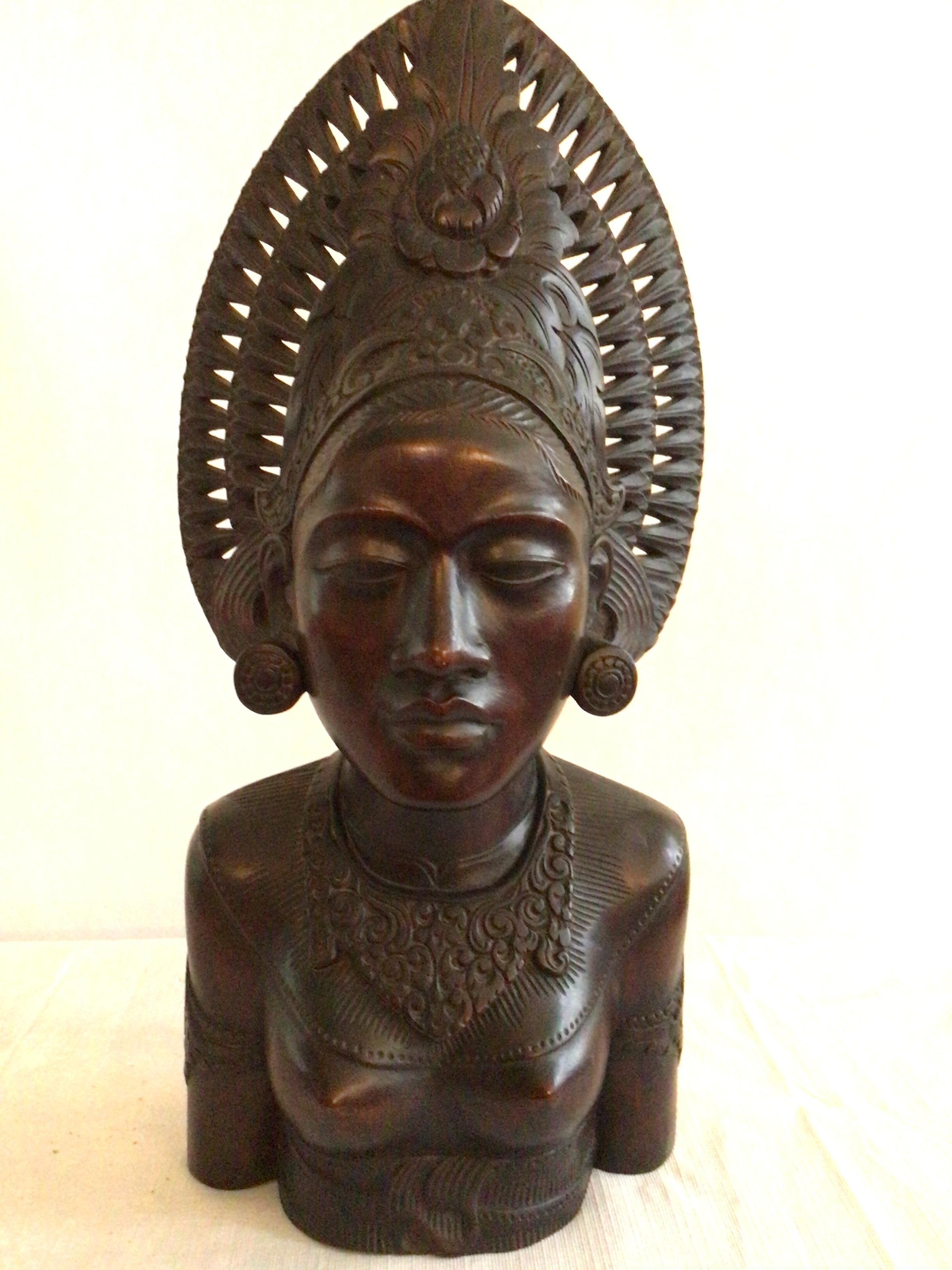 This 1950s finely carved wood statue of a Thai Woman is exquisite from every side. An elaborate headdress with carved openings adds lightness to the piece. Hair is shown tied in the back with a floral rosette. Would look stunning mounted on a Lucite