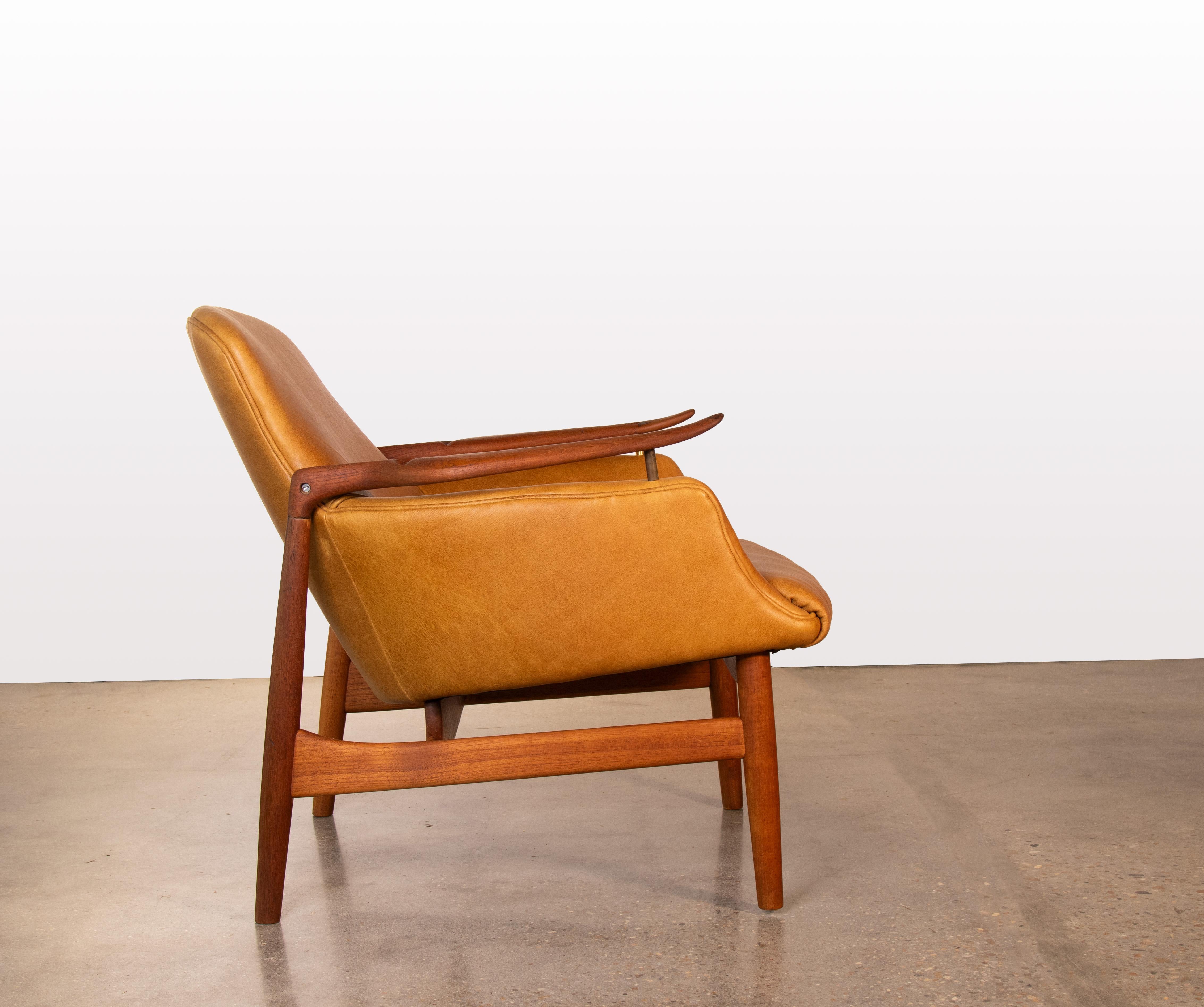 A Finn Juhl NV53 chair in teak and new cognac leather.  An iconic design with floating teak paddle arms with sculpted features.  The arms have the illusion of floating off the seat with brass spacers.  This example imported by Illums Bolighus and