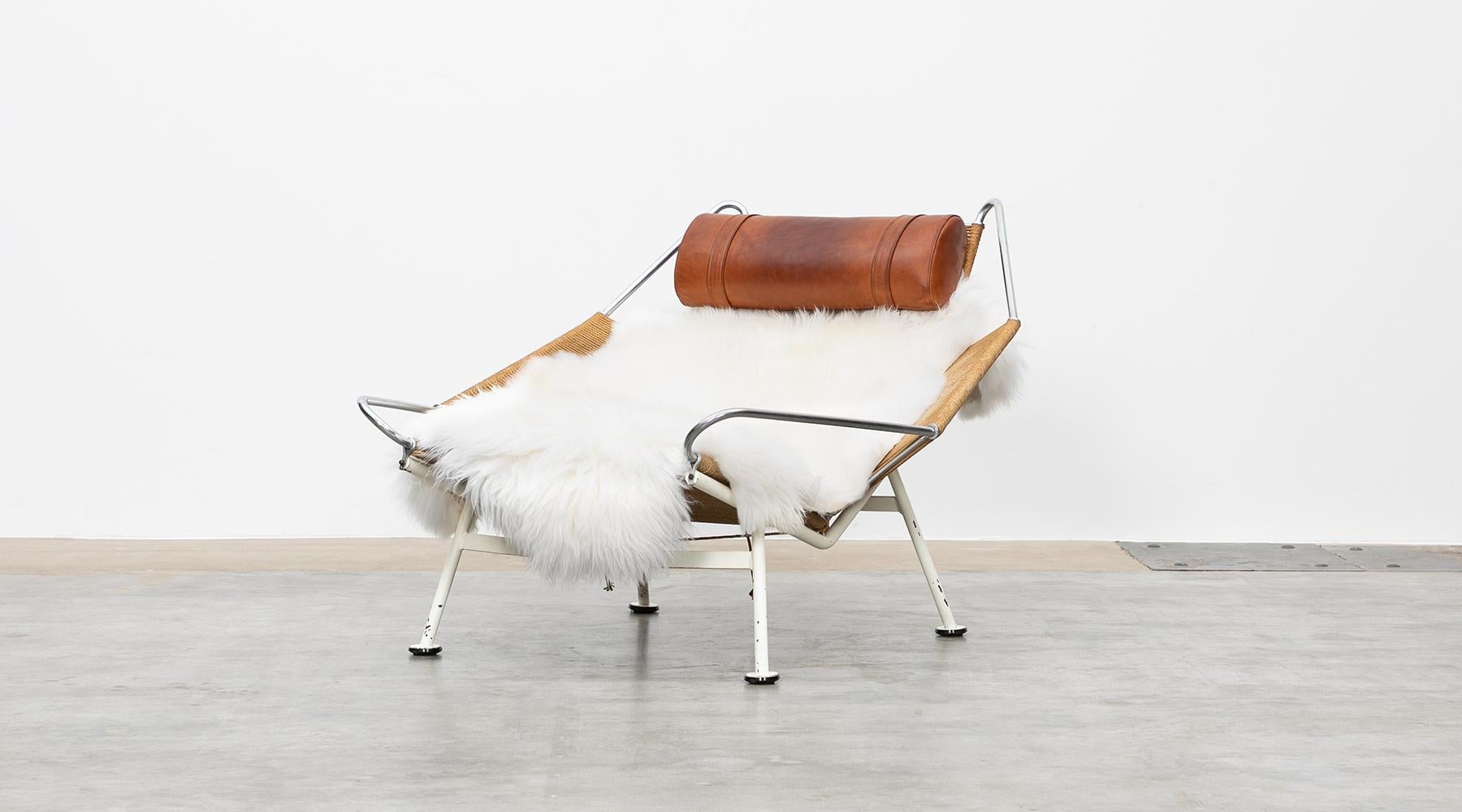 GE225, flag halyard lounge chair, metal, leather by Hans Wegner, Denmark, 1950.

The flag halyard chair has a white lacquered base so that it is visible as a supporting part. The seat shell with flag cord resting on it remained unpainted, so that