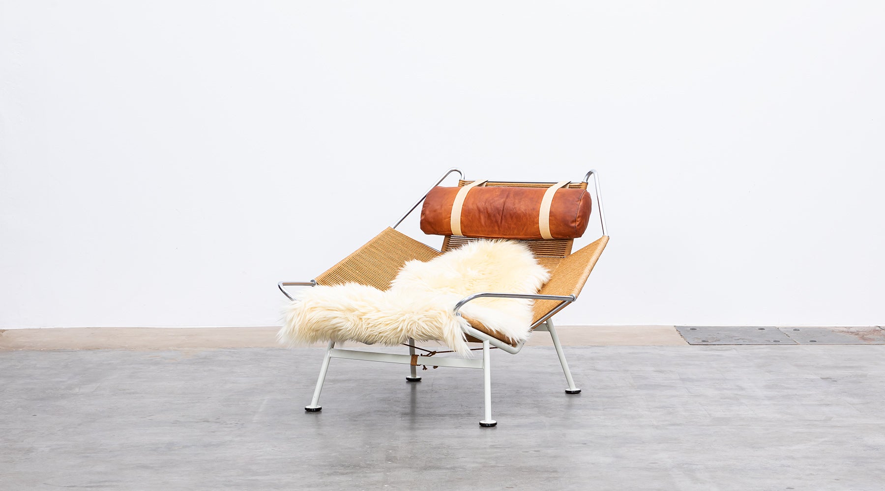 GE225, flag halyard lounge chair, metal, leather by Hans Wegner, Denmark, 1950.

The flag halyard chair has a white lacquered base so that it is visible as a supporting part. The seat shell with flag cord resting on it remained unpainted, so that